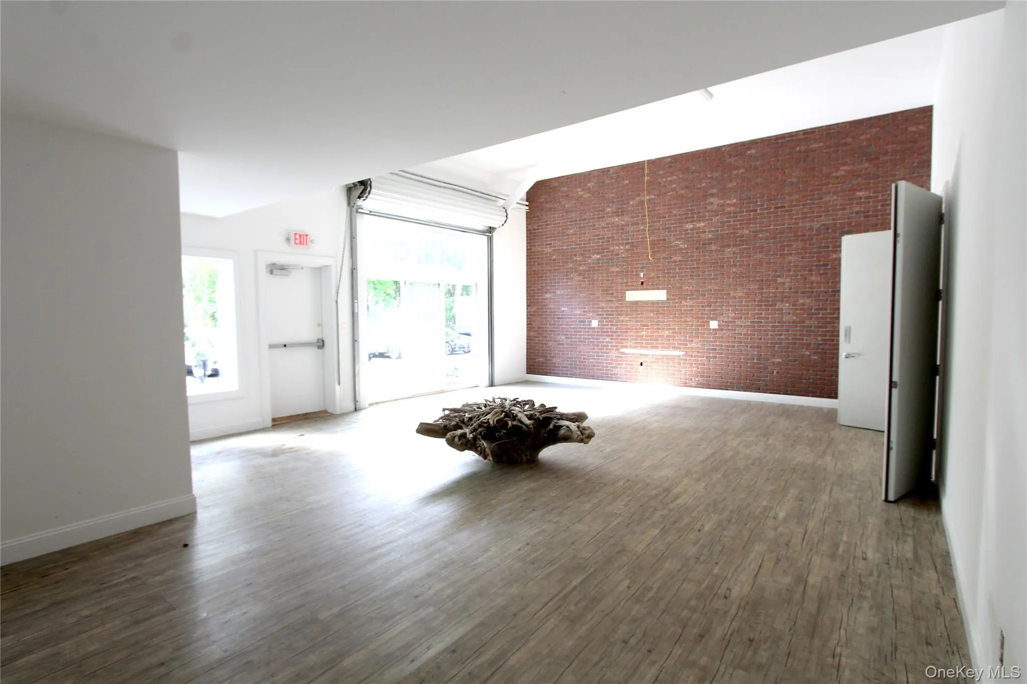 Unfurnished living room with brick wall, wood finished floors, and an accent wall Unfurnished living room with brick wall, wood finished floors, and an accent wall