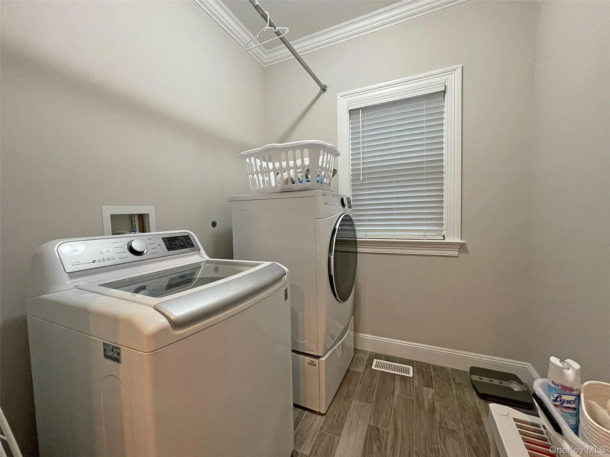 Washroom with crown molding, wood tiled floors, and washing machine and dryer Washroom with crown molding, wood tiled floors, and washing machine and dryer