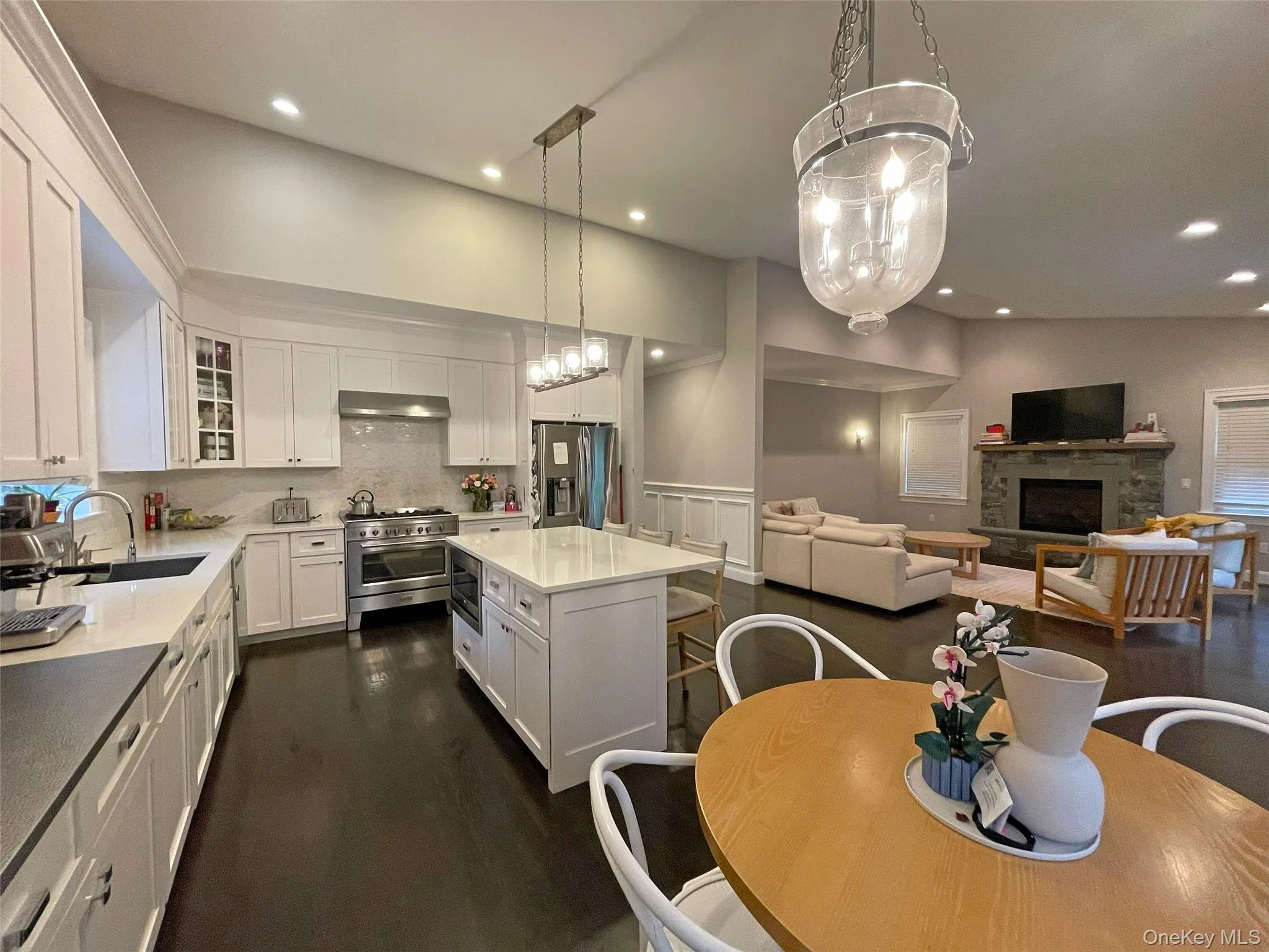 Kitchen featuring stainless steel appliances, white cabinets, hanging light fixtures, and a center island Kitchen featuring stainless steel appliances, white cabinets, hanging light fixtures, and a center island