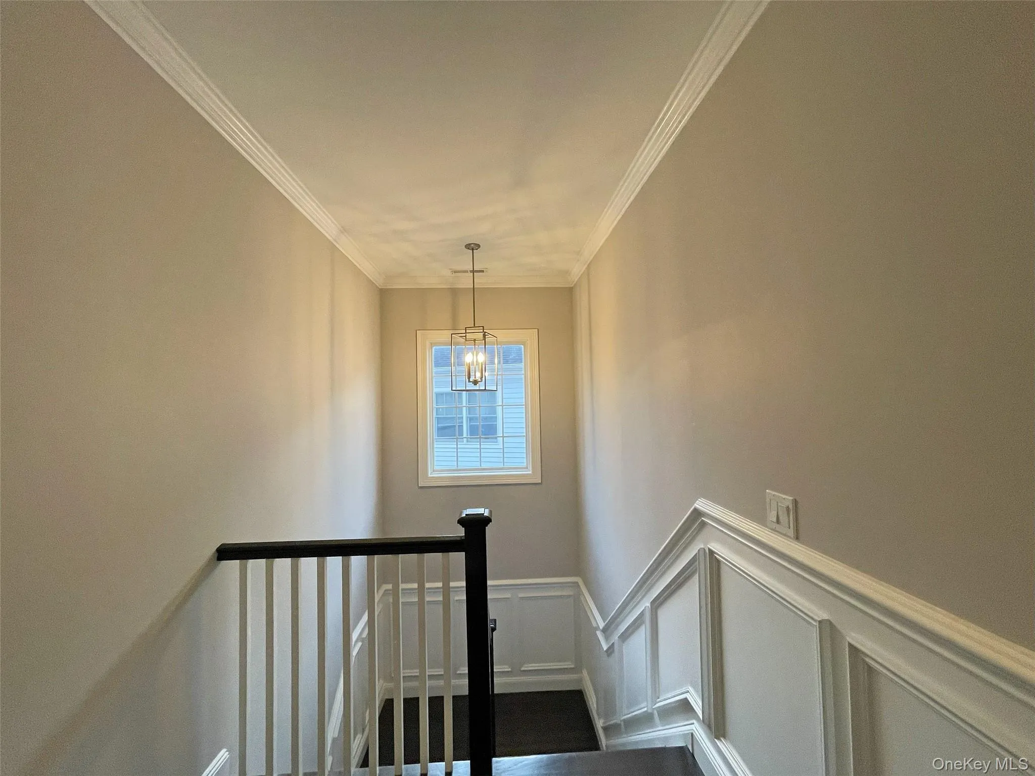 Staircase featuring crown molding, a decorative wall, and wainscoting Staircase featuring crown molding, a decorative wall, and wainscoting
