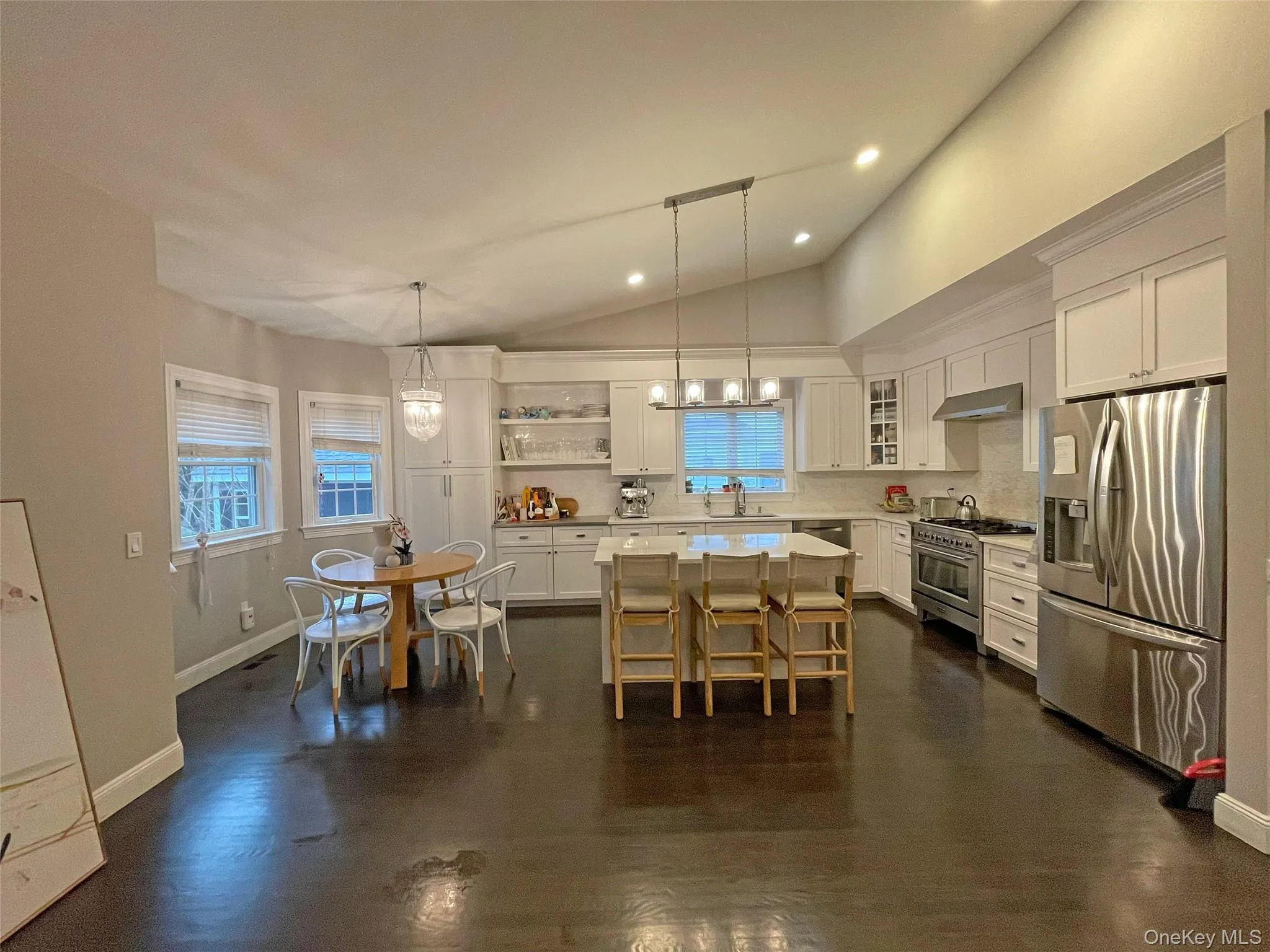 Kitchen with hanging light fixtures, white cabinetry, appliances with stainless steel finishes, and a center island. Kitchen with hanging light fixtures, white cabinetry, appliances with stainless steel finishes, and a center island.