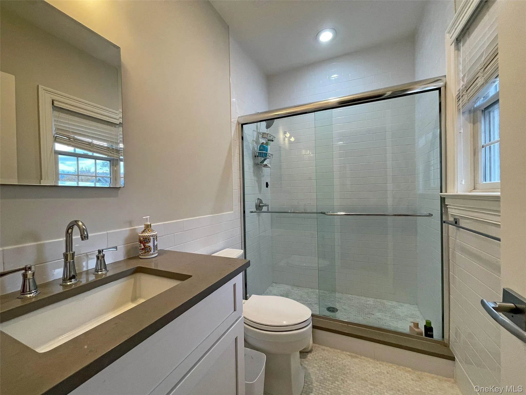 Bathroom featuring vanity, a stall shower, and wainscoting Bathroom featuring vanity, a stall shower, and wainscoting