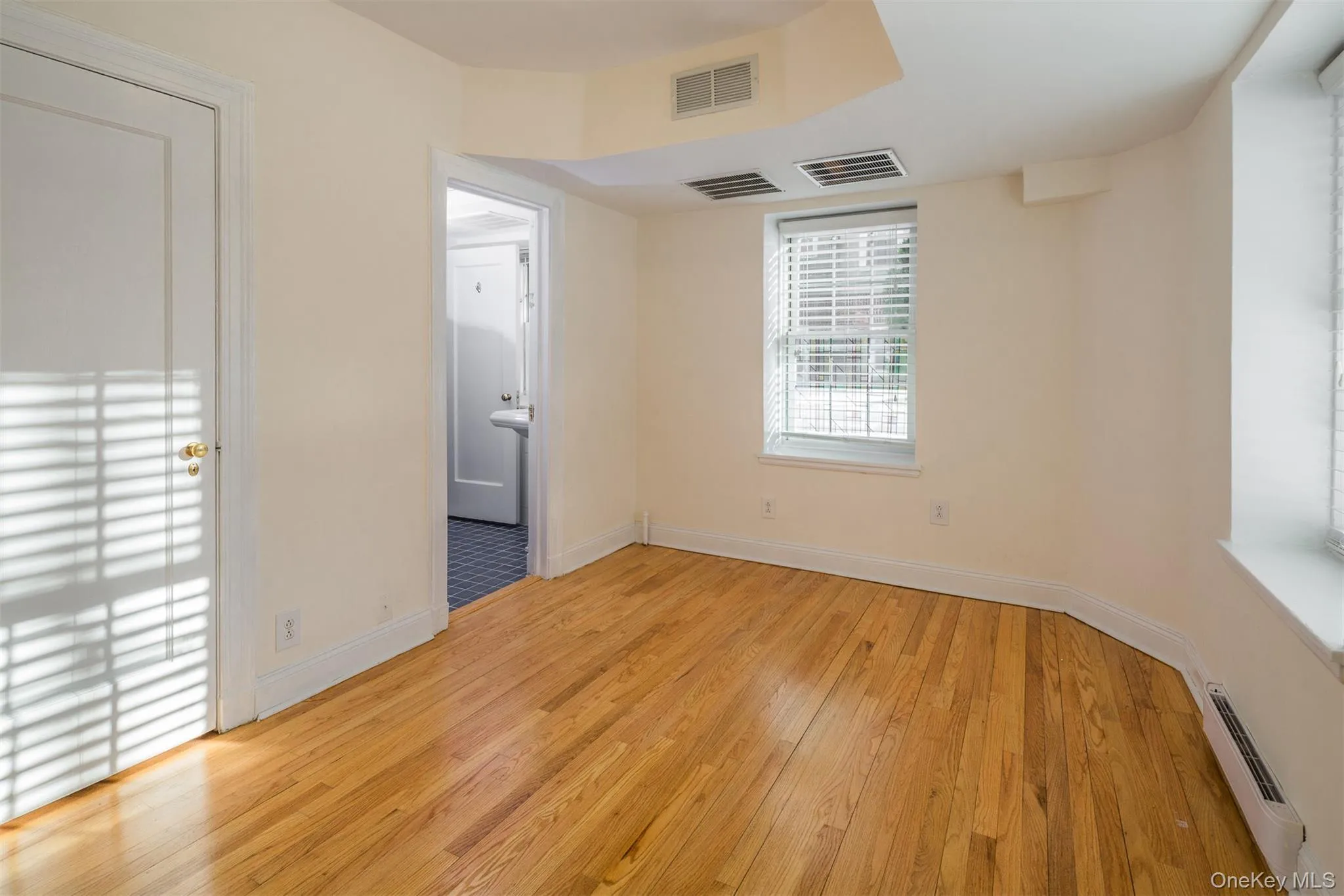 Unfurnished bedroom with a baseboard radiator and light wood-type flooring Unfurnished bedroom with a baseboard radiator and light wood-type flooring