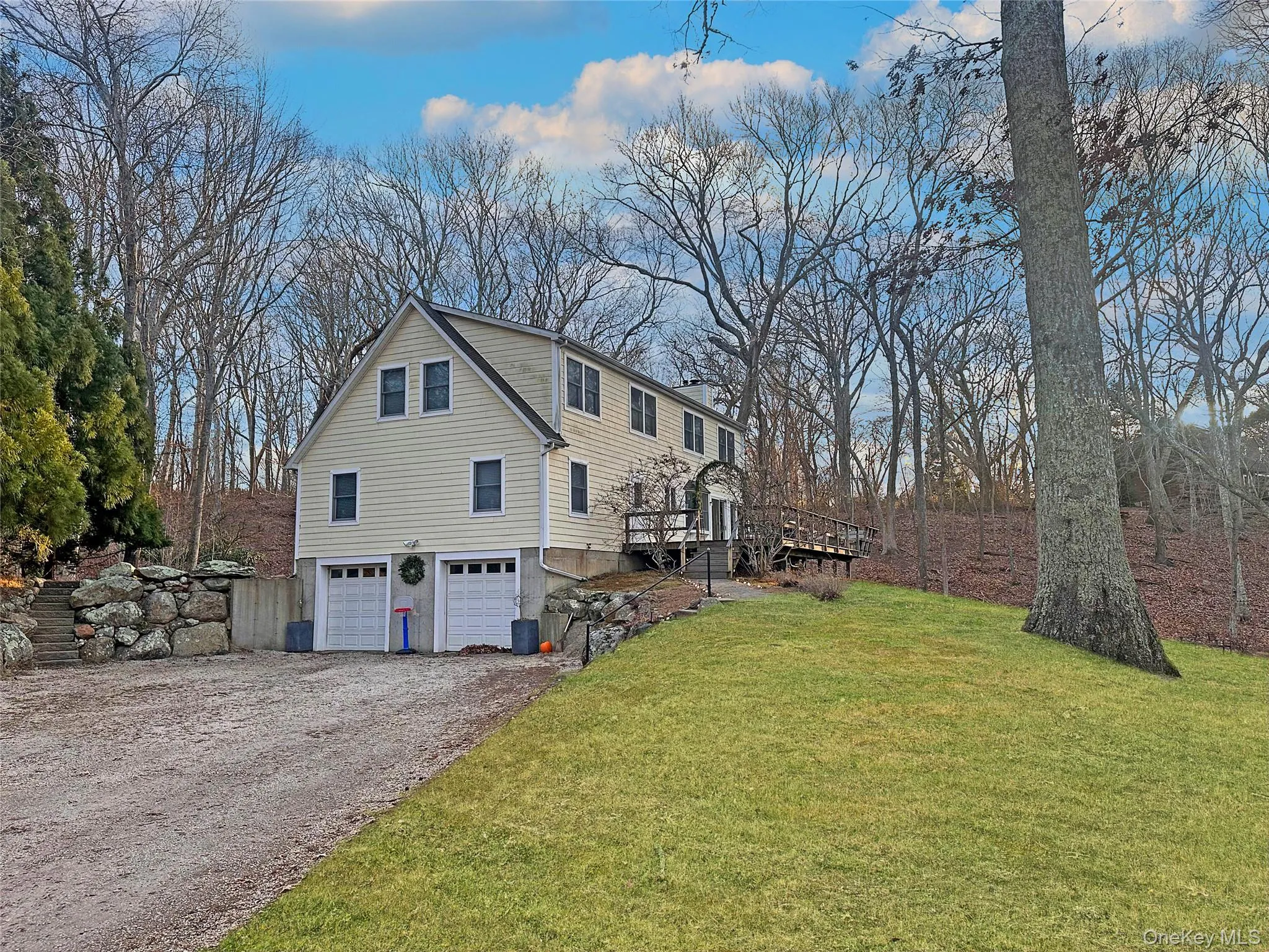 View of property exterior featuring a yard, an attached garage, a wooden deck, driveway, and a chimney View of property exterior featuring a yard, an attached garage, a wooden deck, driveway, and a chimney