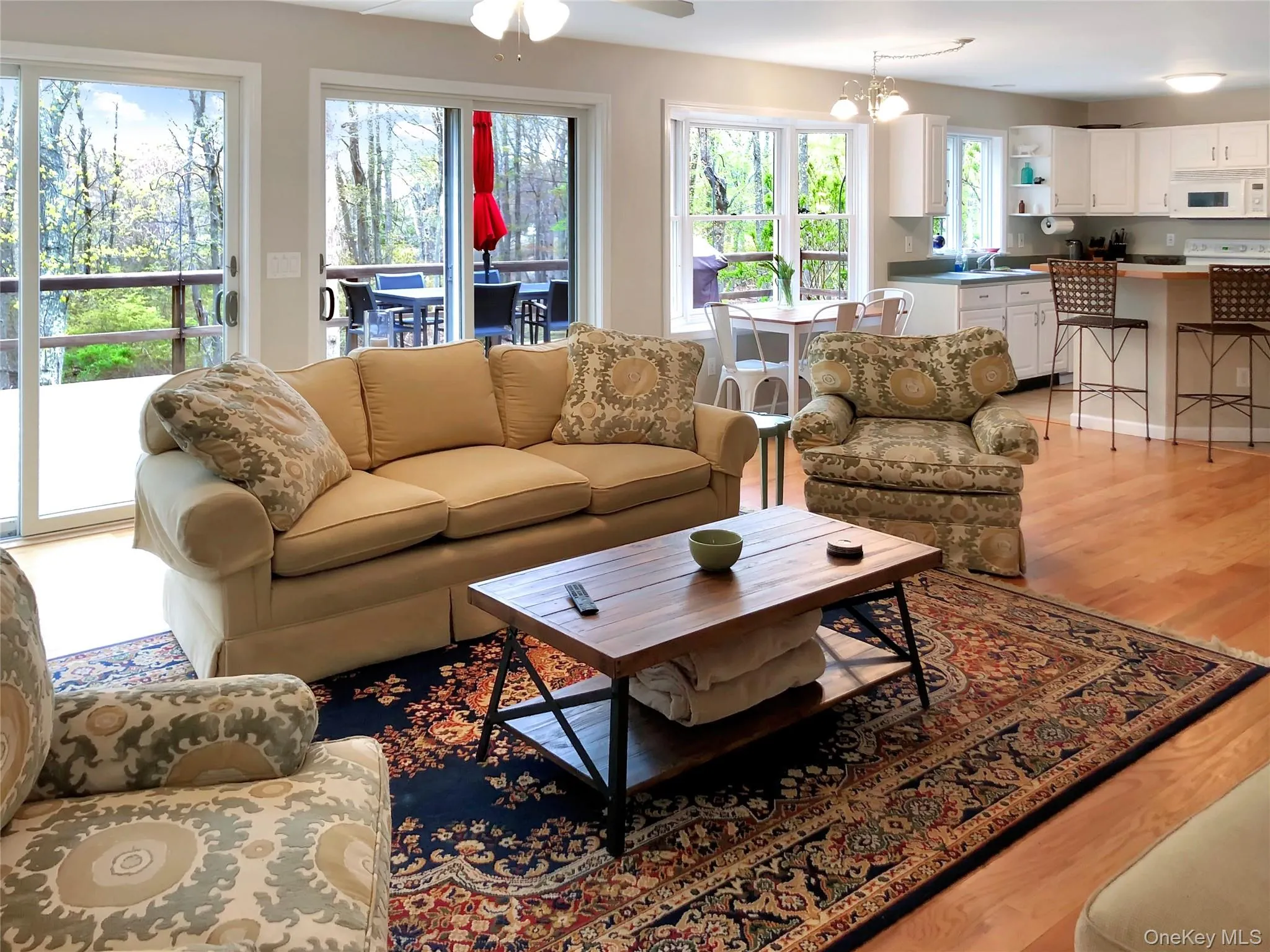 Living room with light wood-style floors, a ceiling fan, and a chandelier Living room with light wood-style floors, a ceiling fan, and a chandelier