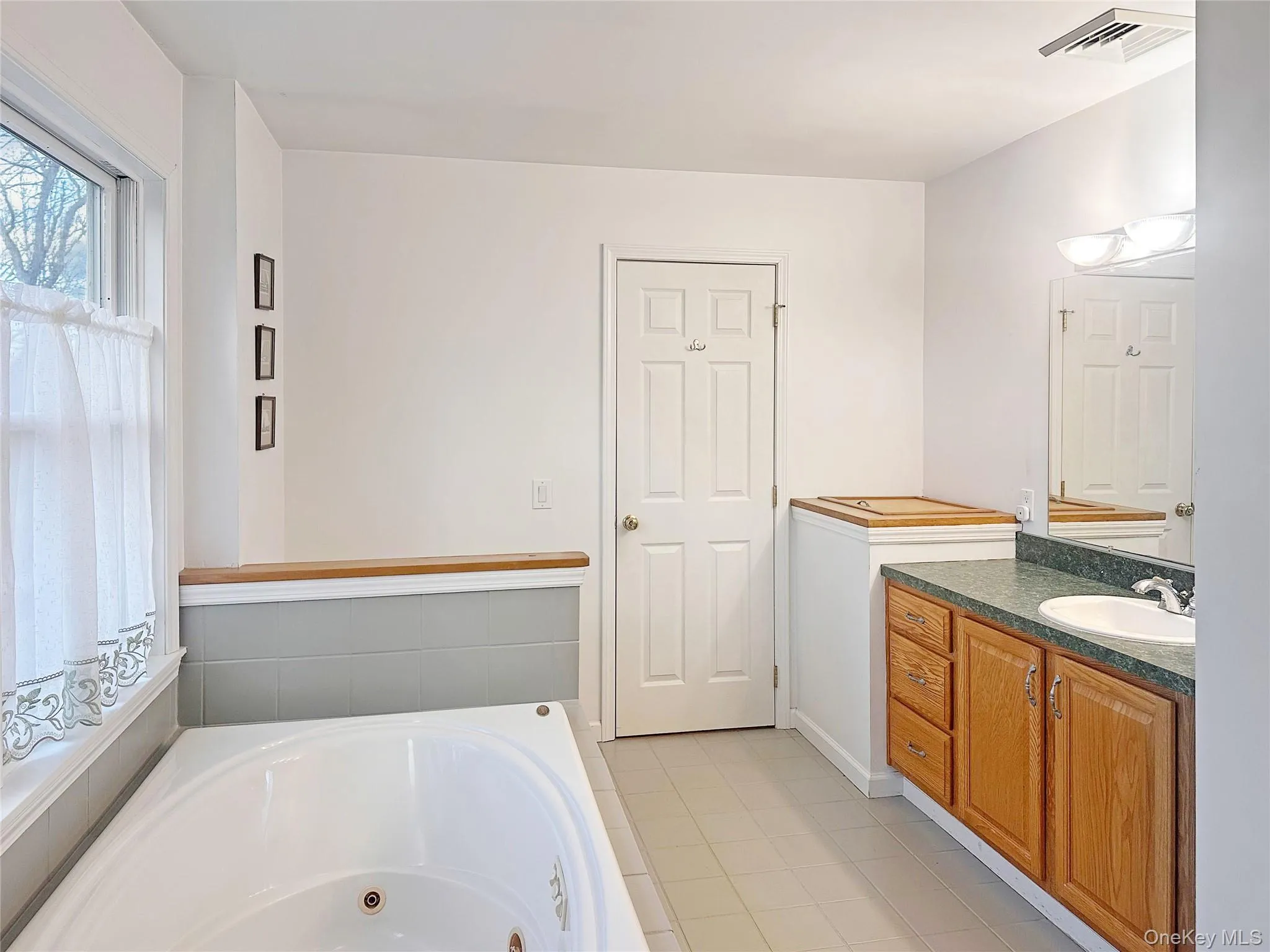 Bathroom featuring a jetted tub, vanity, and light tile patterned flooring Bathroom featuring a jetted tub, vanity, and light tile patterned flooring