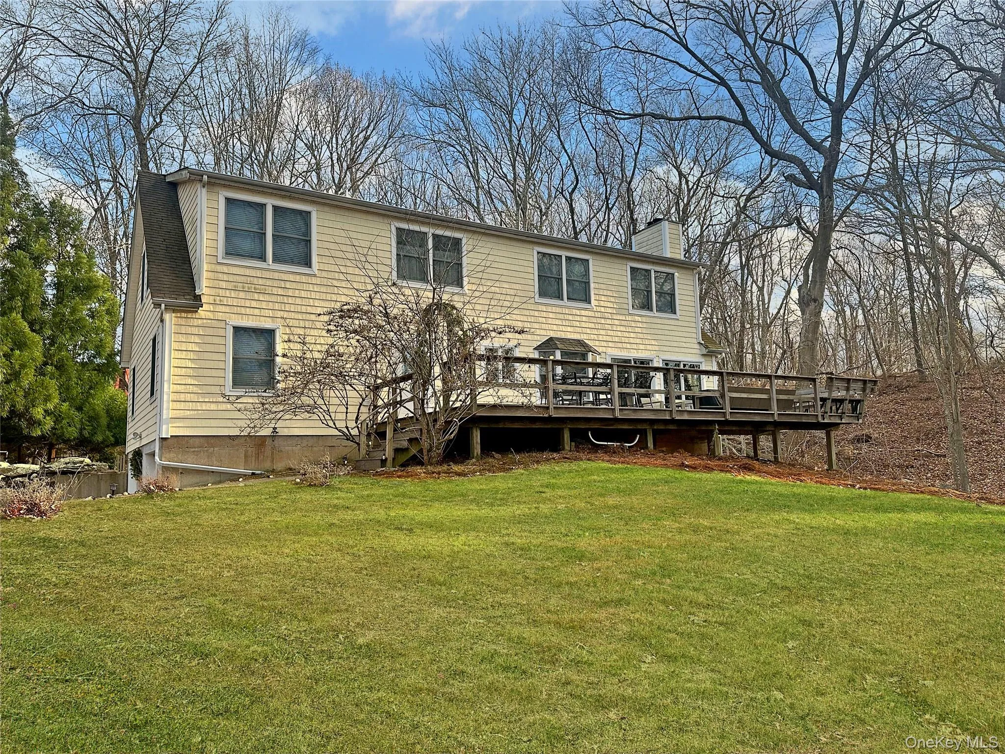 Rear view of house with a yard, a wooden deck, and a chimney Rear view of house with a yard, a wooden deck, and a chimney