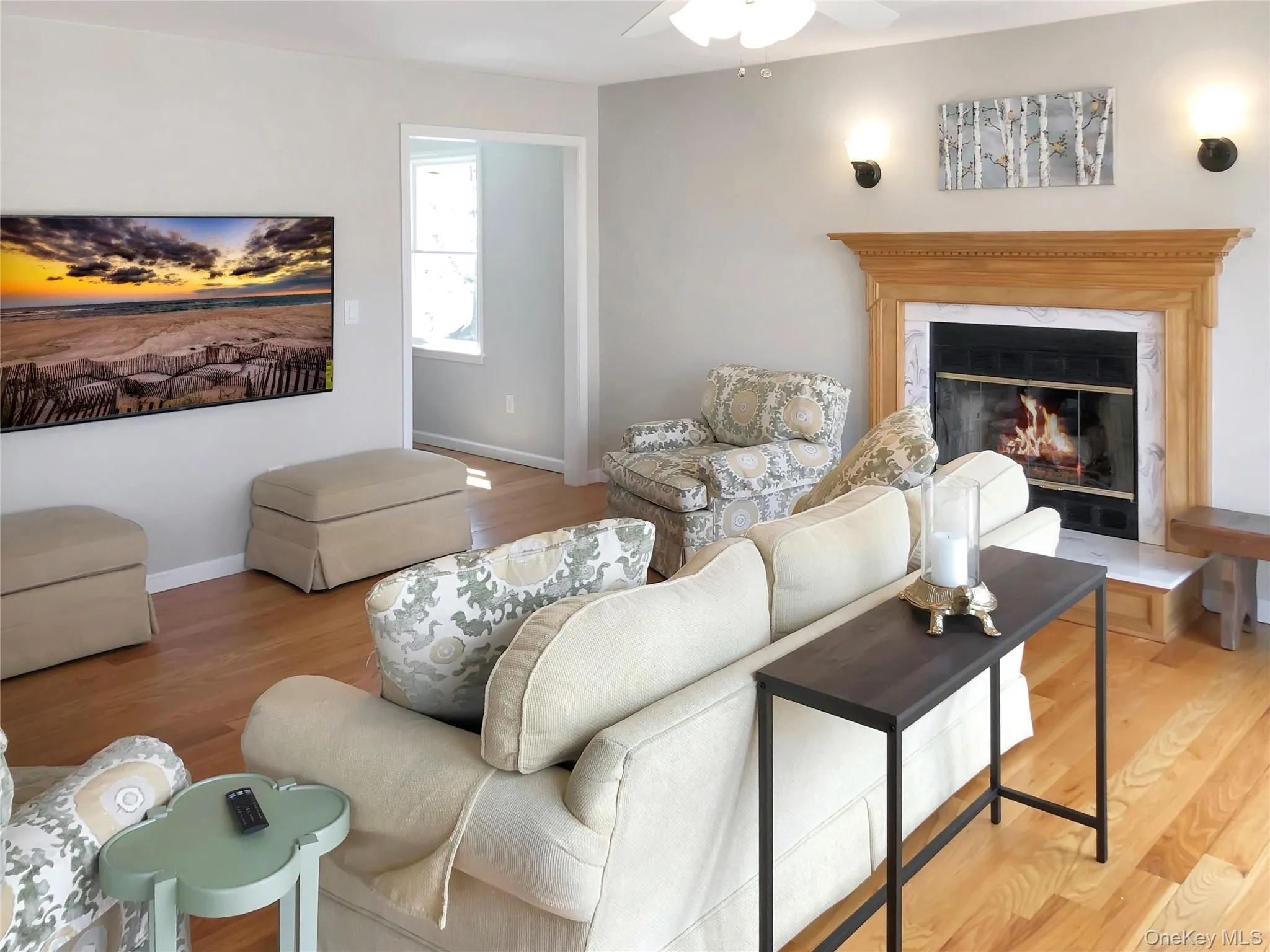 Living room with wood finished floors, a high end fireplace, and a ceiling fan Living room with wood finished floors, a high end fireplace, and a ceiling fan
