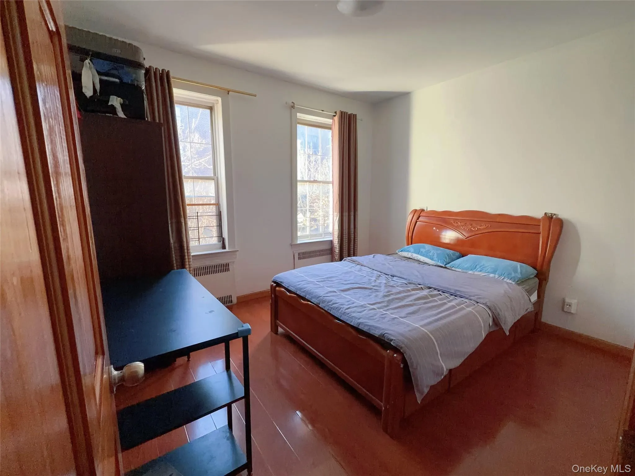 Bedroom featuring hardwood / wood-style floors and radiator Bedroom featuring hardwood / wood-style floors and radiator