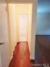 Corridor featuring dark wood finished floors and baseboards Corridor featuring dark wood finished floors and baseboards