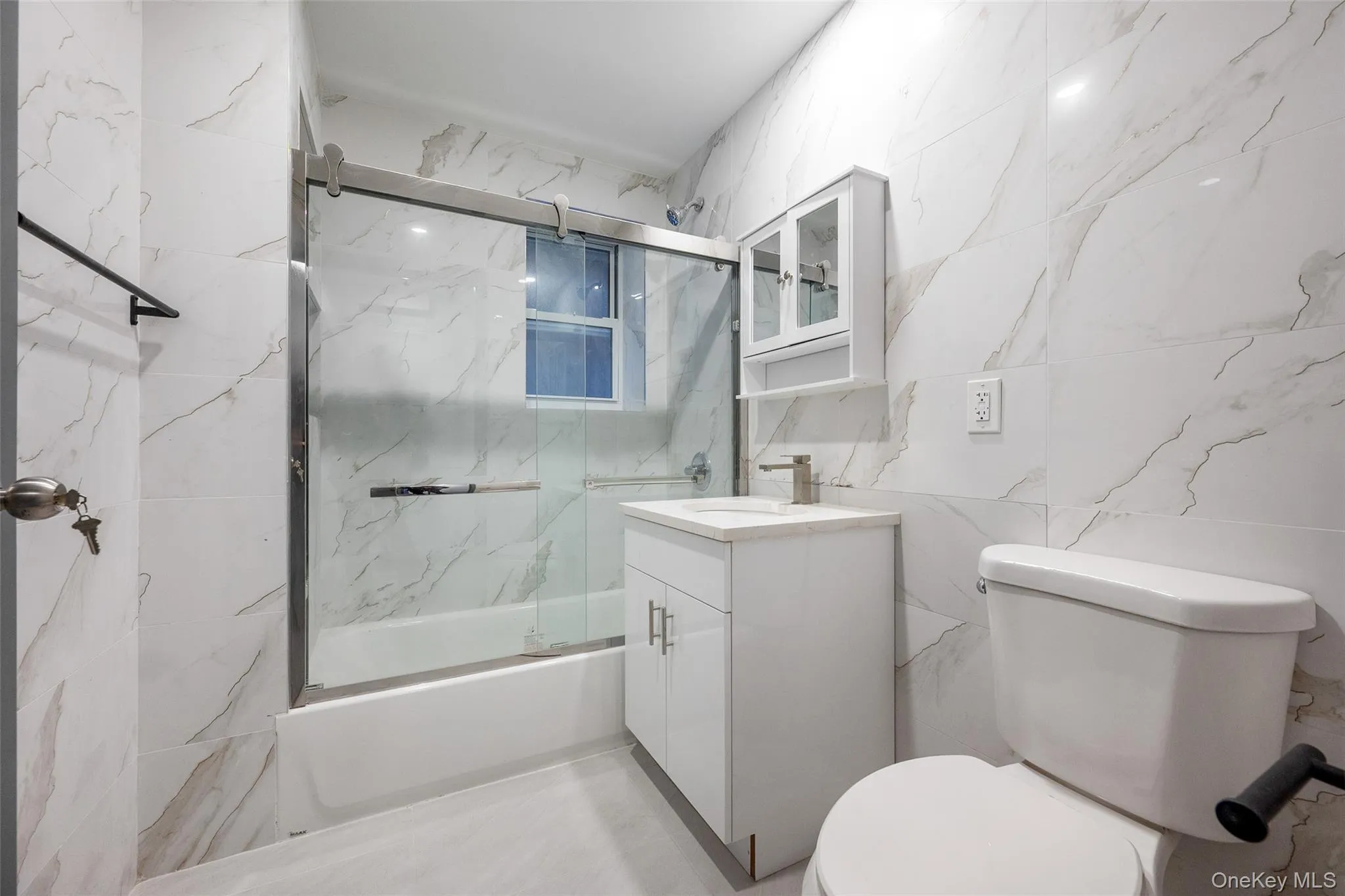 Bathroom with tile walls, bath / shower combo with glass door, and vanity Bathroom with tile walls, bath / shower combo with glass door, and vanity