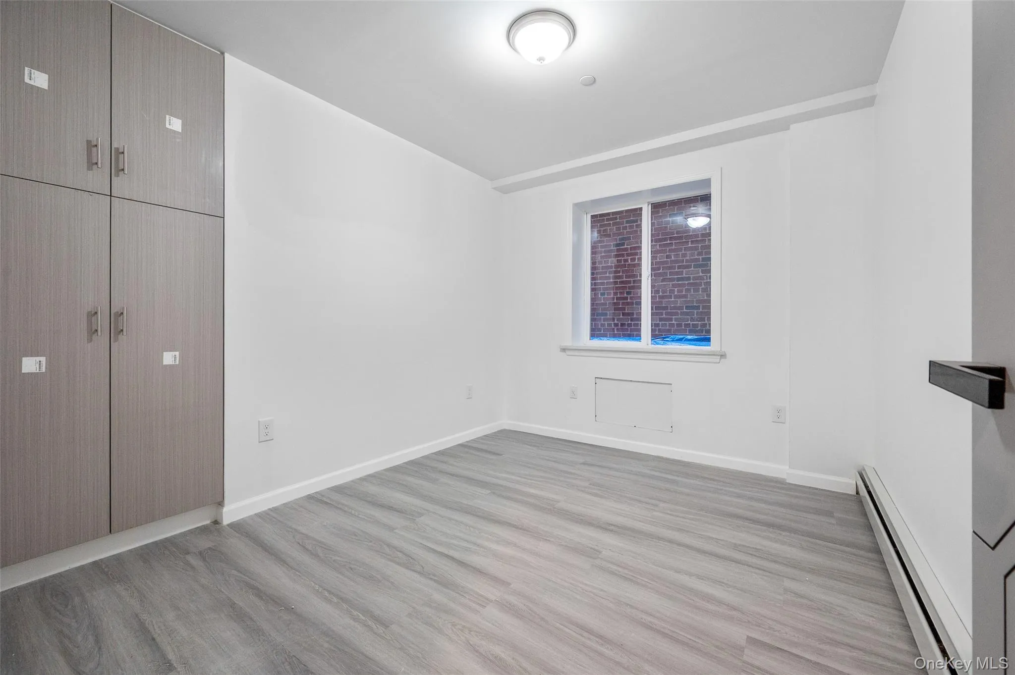 Unfurnished bedroom featuring a baseboard heating unit and light wood finished floors Unfurnished bedroom featuring a baseboard heating unit and light wood finished floors