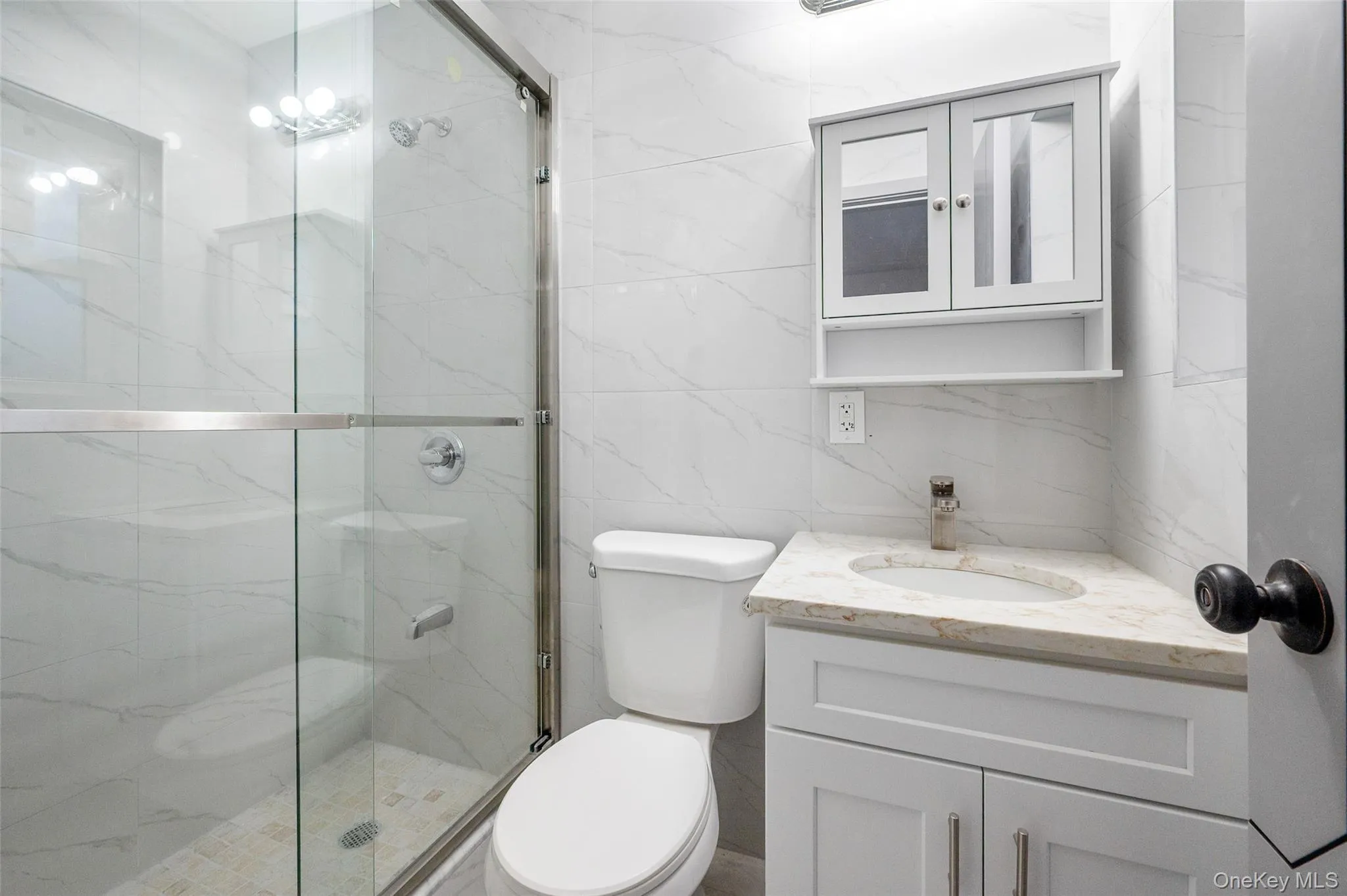 Full bathroom featuring tile walls, a marble finish shower, and vanity Full bathroom featuring tile walls, a marble finish shower, and vanity