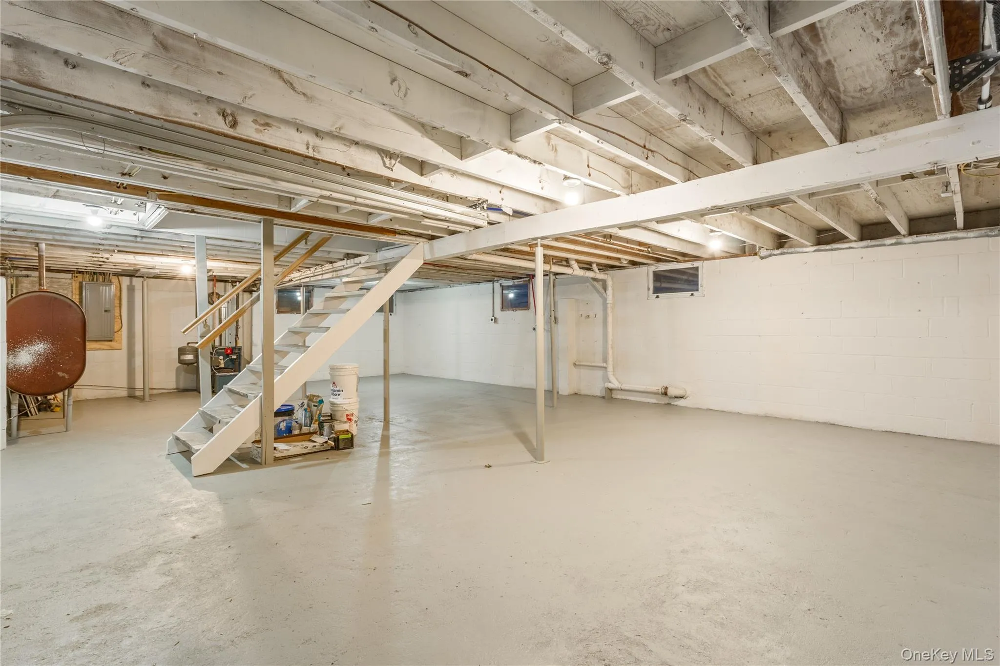 Unfinished below grade area with stairs, oil tank, and electric panel Unfinished below grade area with stairs, oil tank, and electric panel