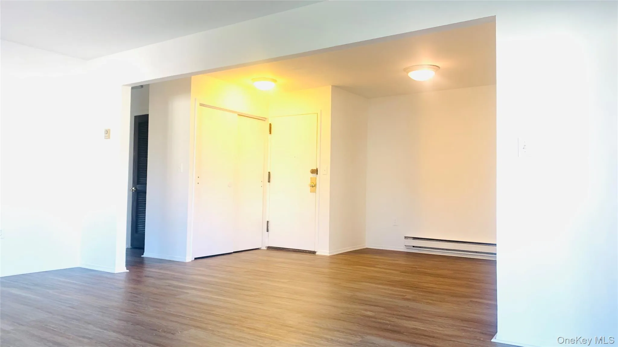 Spare room with wood finished floors and a baseboard heating unit Spare room with wood finished floors and a baseboard heating unit
