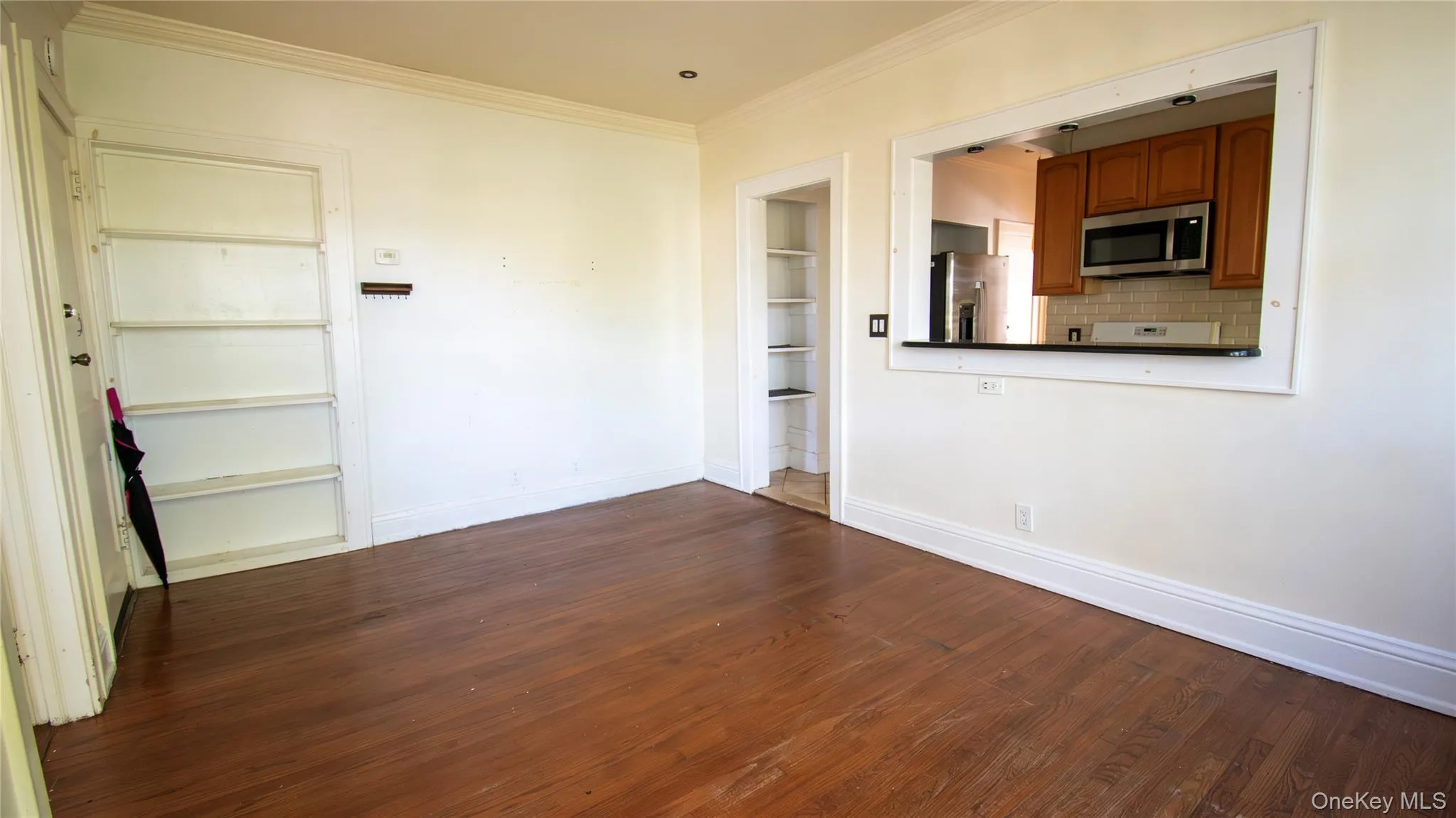 Spare room featuring dark wood finished floors, crown molding, and built in features Spare room featuring dark wood finished floors, crown molding, and built in features
