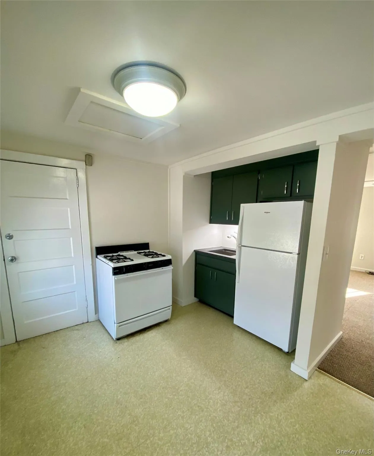 Kitchen with green cabinetry, white appliances, and light flooring Kitchen with green cabinetry, white appliances, and light flooring