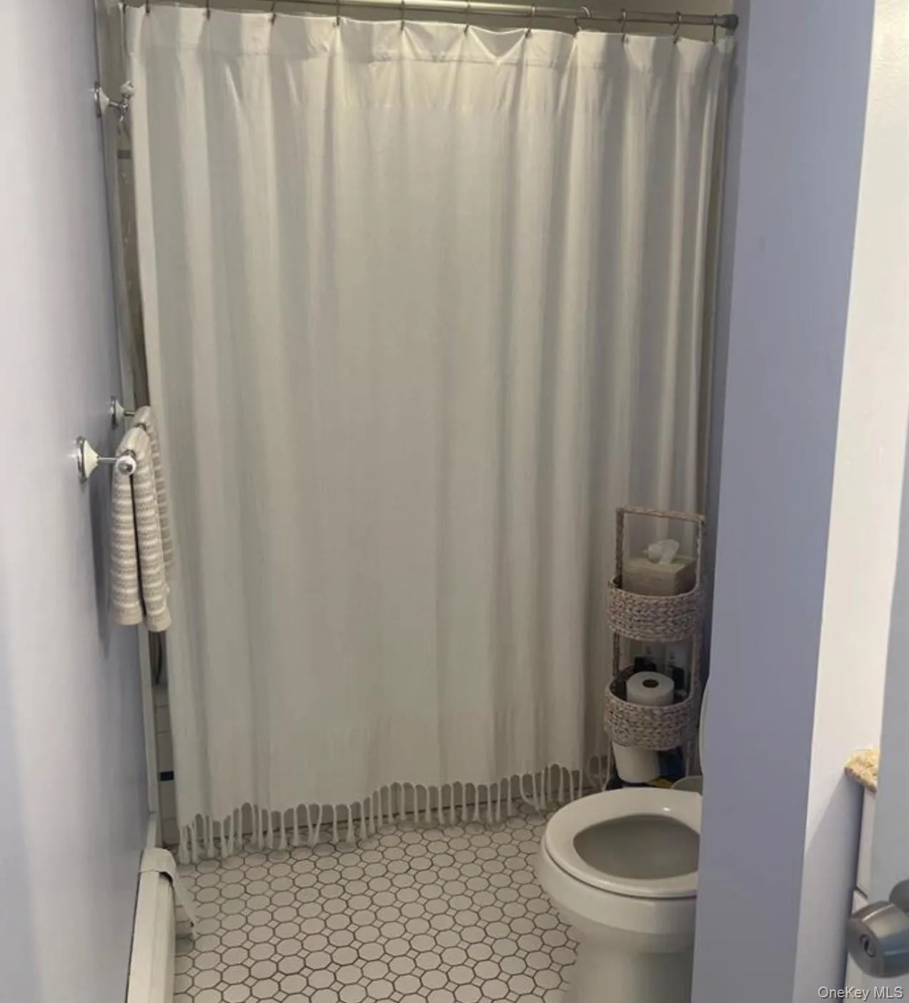 Full bathroom with a shower with shower curtain and a baseboard radiator Full bathroom with a shower with shower curtain and a baseboard radiator
