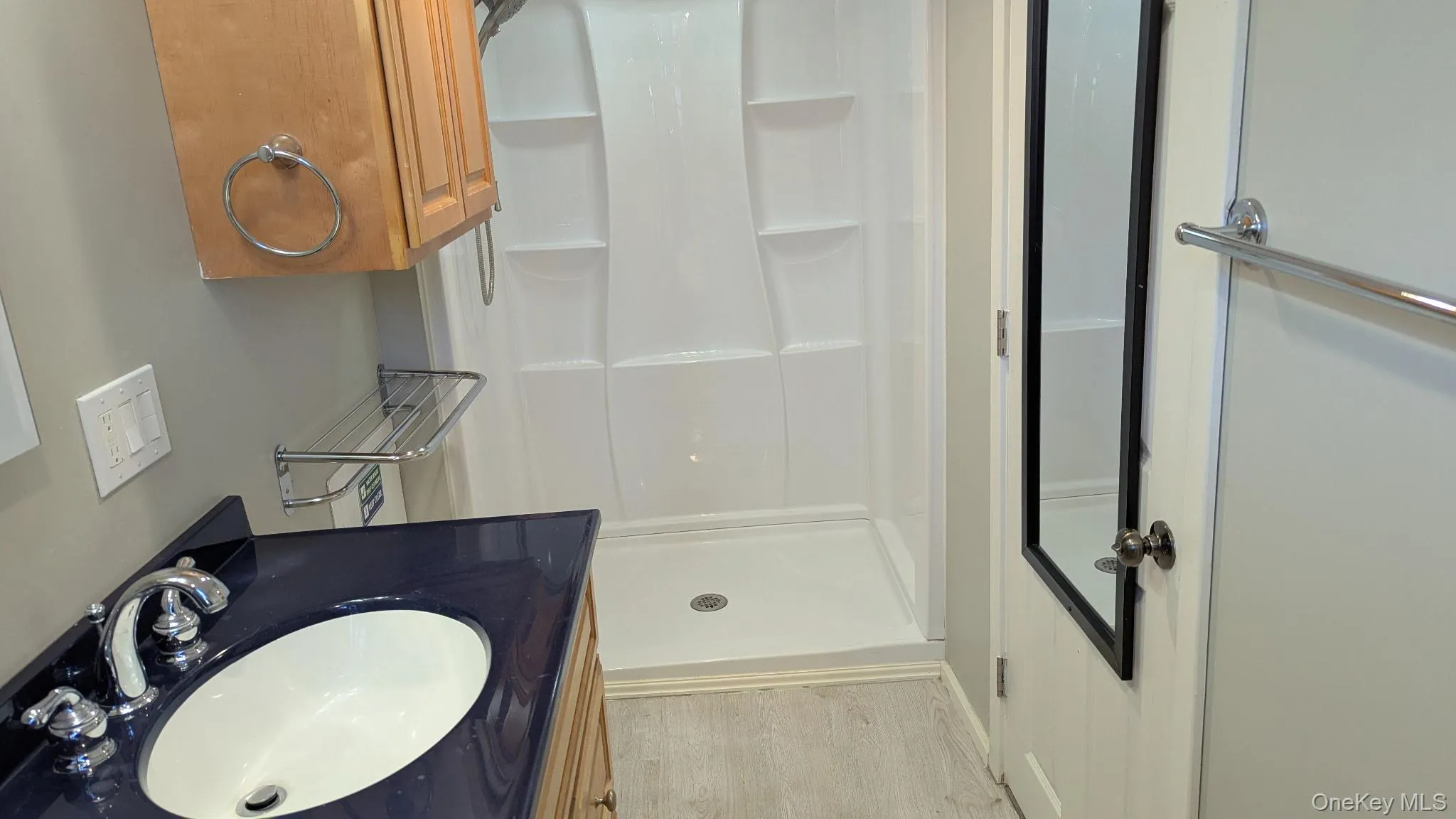 Full bath with a shower stall, vanity, and light wood-style flooring Full bath with a shower stall, vanity, and light wood-style flooring
