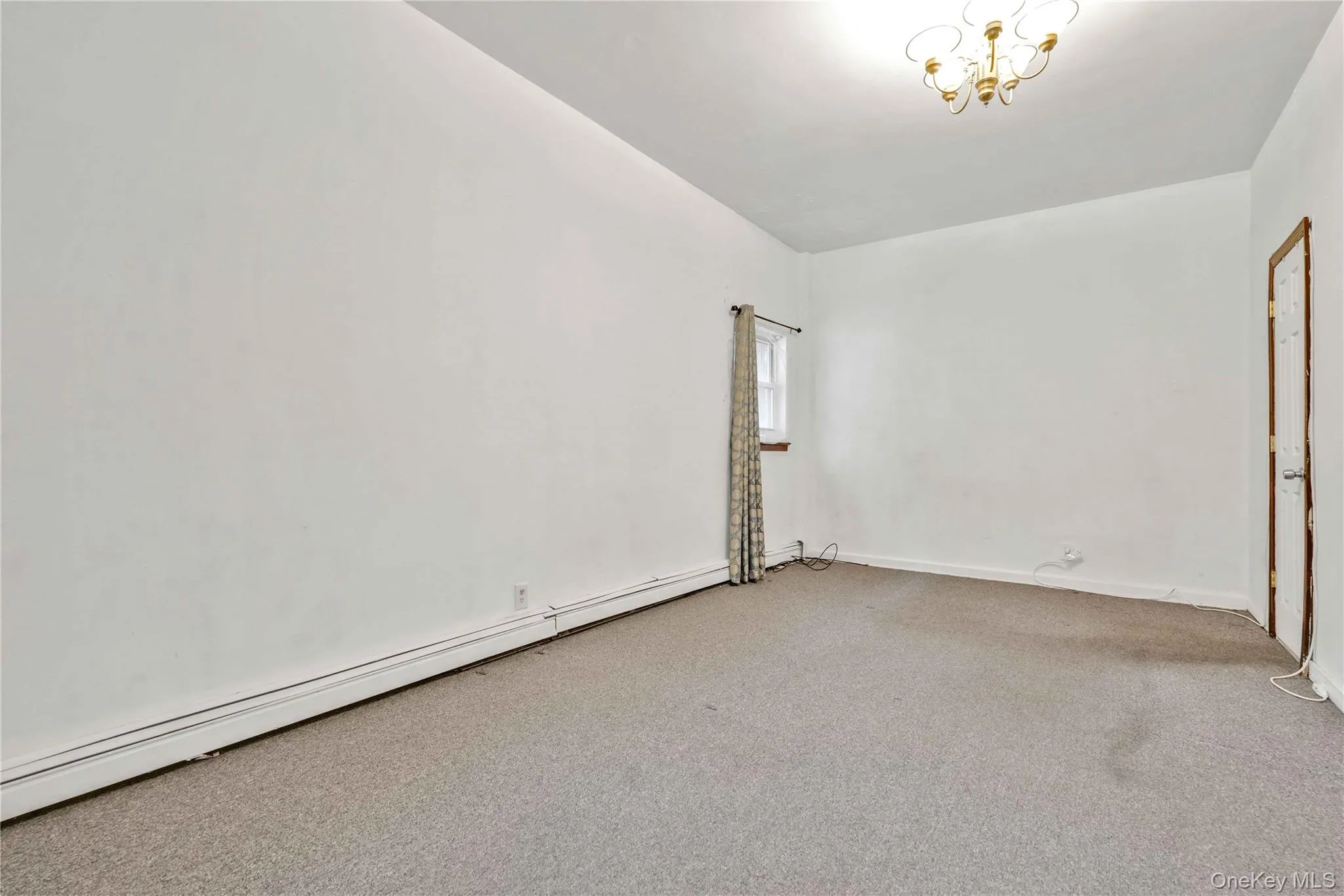 Unfurnished room with baseboard heating, carpet flooring, and a chandelier Unfurnished room with baseboard heating, carpet flooring, and a chandelier