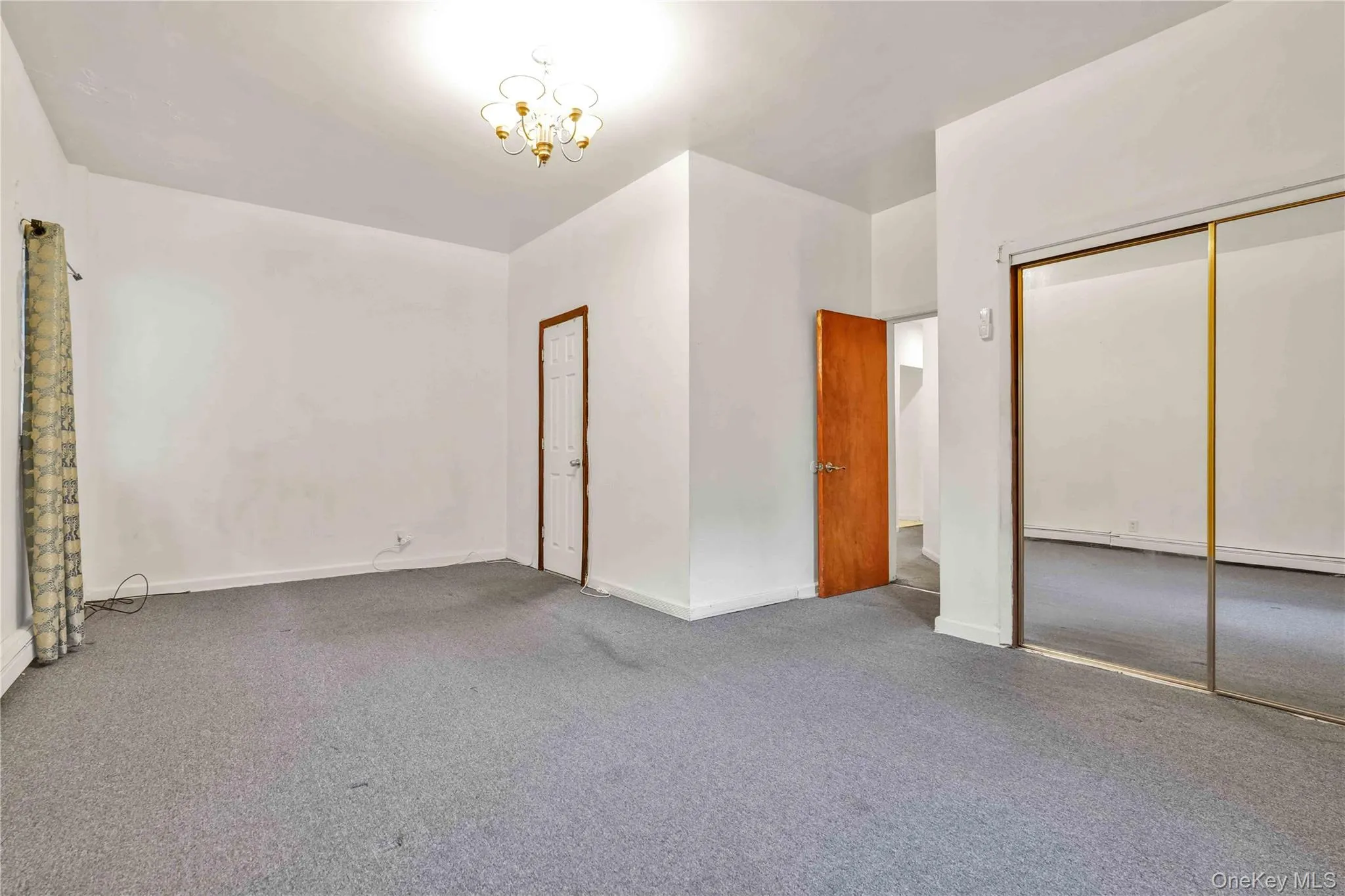 Unfurnished bedroom featuring carpet flooring, a chandelier, and a baseboard heating unit Unfurnished bedroom featuring carpet flooring, a chandelier, and a baseboard heating unit