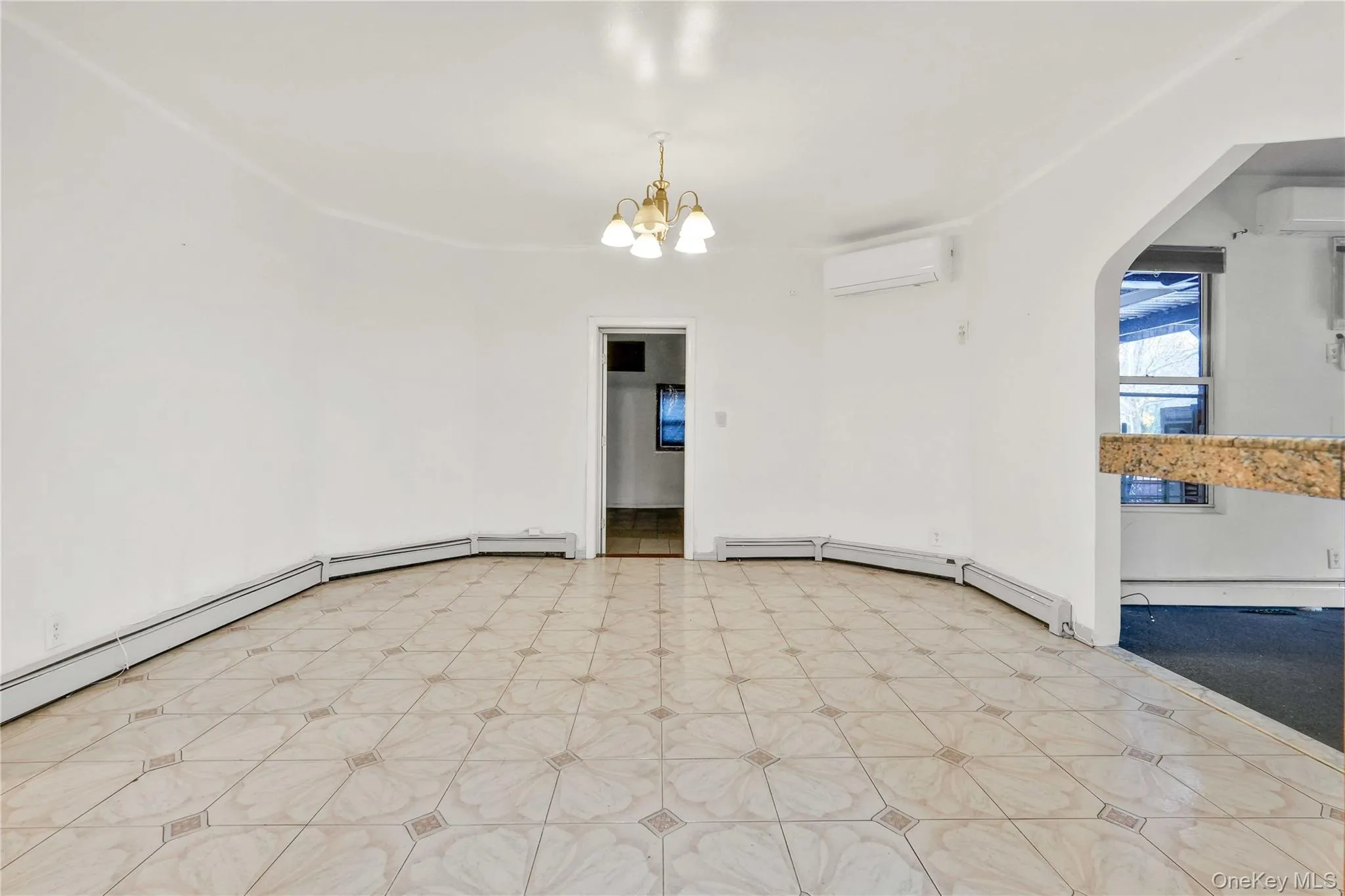 Unfurnished room featuring baseboard heating, arched walkways, a wall mounted AC, and a chandelier Unfurnished room featuring baseboard heating, arched walkways, a wall mounted AC, and a chandelier