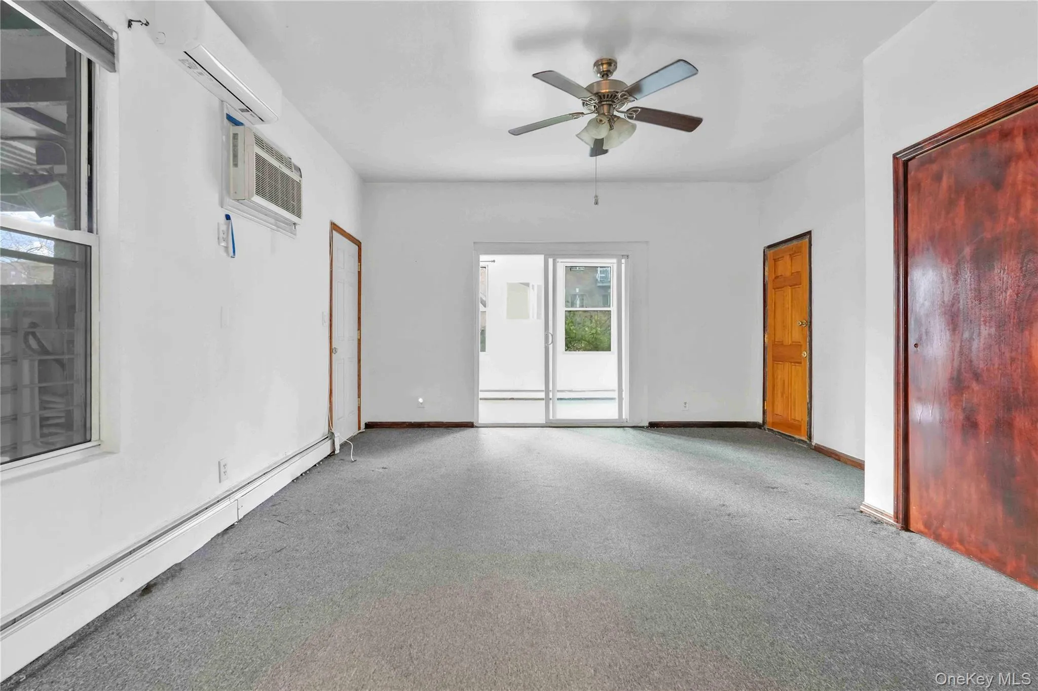 Carpeted spare room with baseboard heating, a ceiling fan, a wall mounted AC, and a wall mounted air conditioner Carpeted spare room with baseboard heating, a ceiling fan, a wall mounted AC, and a wall mounted air conditioner
