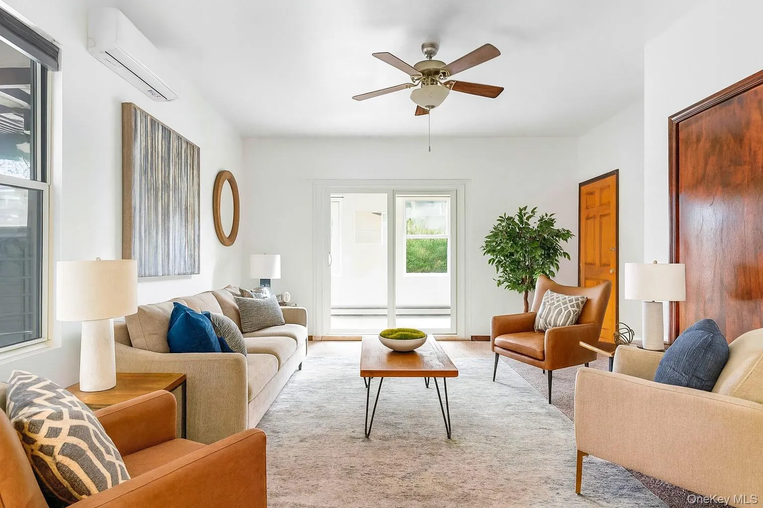 Living area featuring a wall mounted AC, ceiling fan, and light carpet Living area featuring a wall mounted AC, ceiling fan, and light carpet