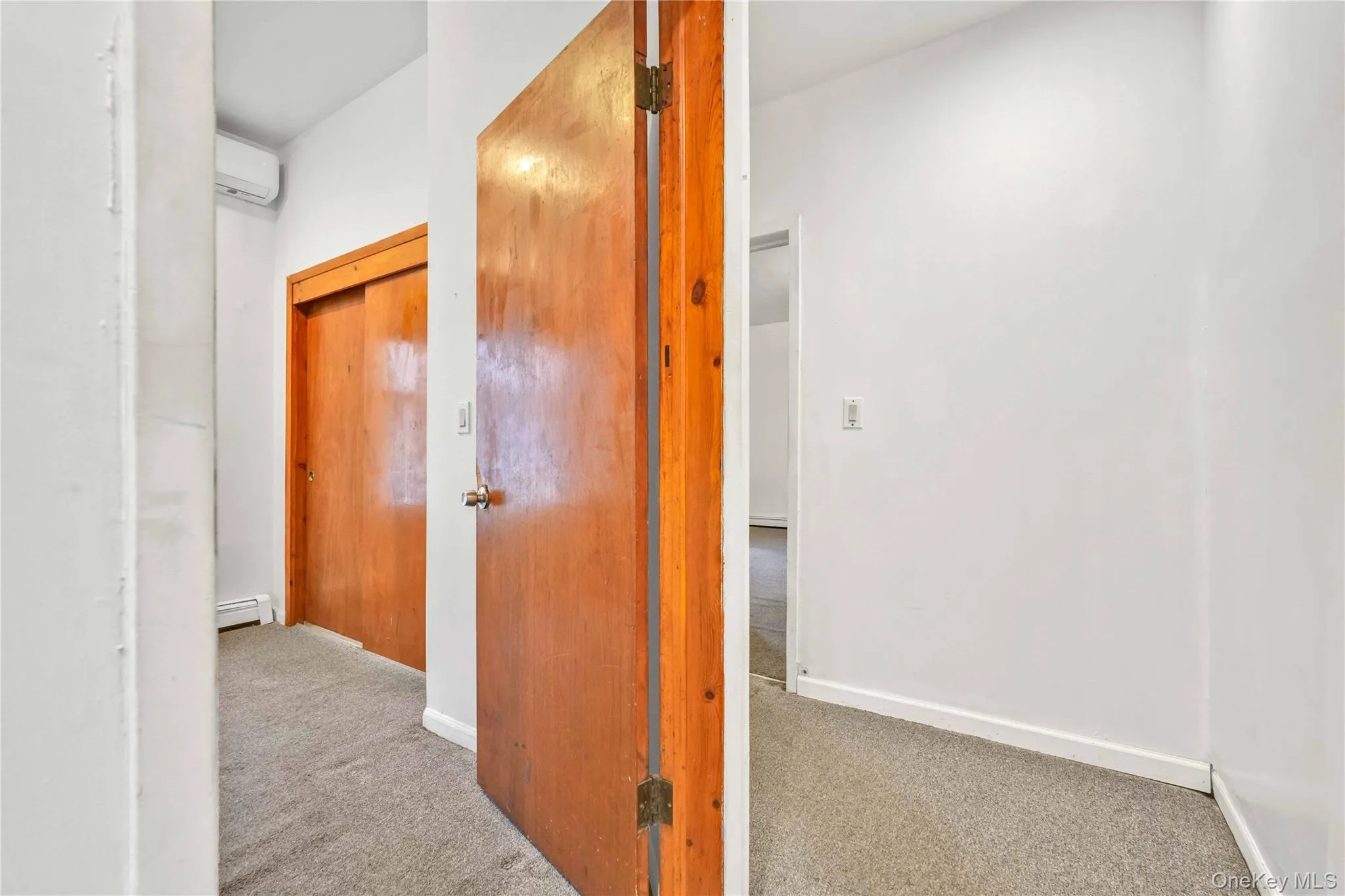 Hall with carpet flooring, a wall mounted air conditioner, and baseboard heating Hall with carpet flooring, a wall mounted air conditioner, and baseboard heating