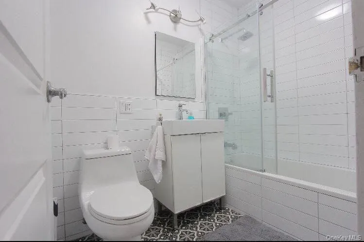 Full bath with vanity, tiled shower / bath, tile walls, and wainscoting Full bath with vanity, tiled shower / bath, tile walls, and wainscoting