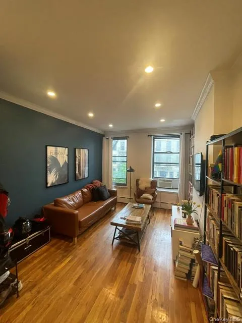 Living area with ornamental molding, hardwood / wood-style floors, recessed lighting, a baseboard radiator, and baseboard heating Living area with ornamental molding, hardwood / wood-style floors, recessed lighting, a baseboard radiator, and baseboard heating
