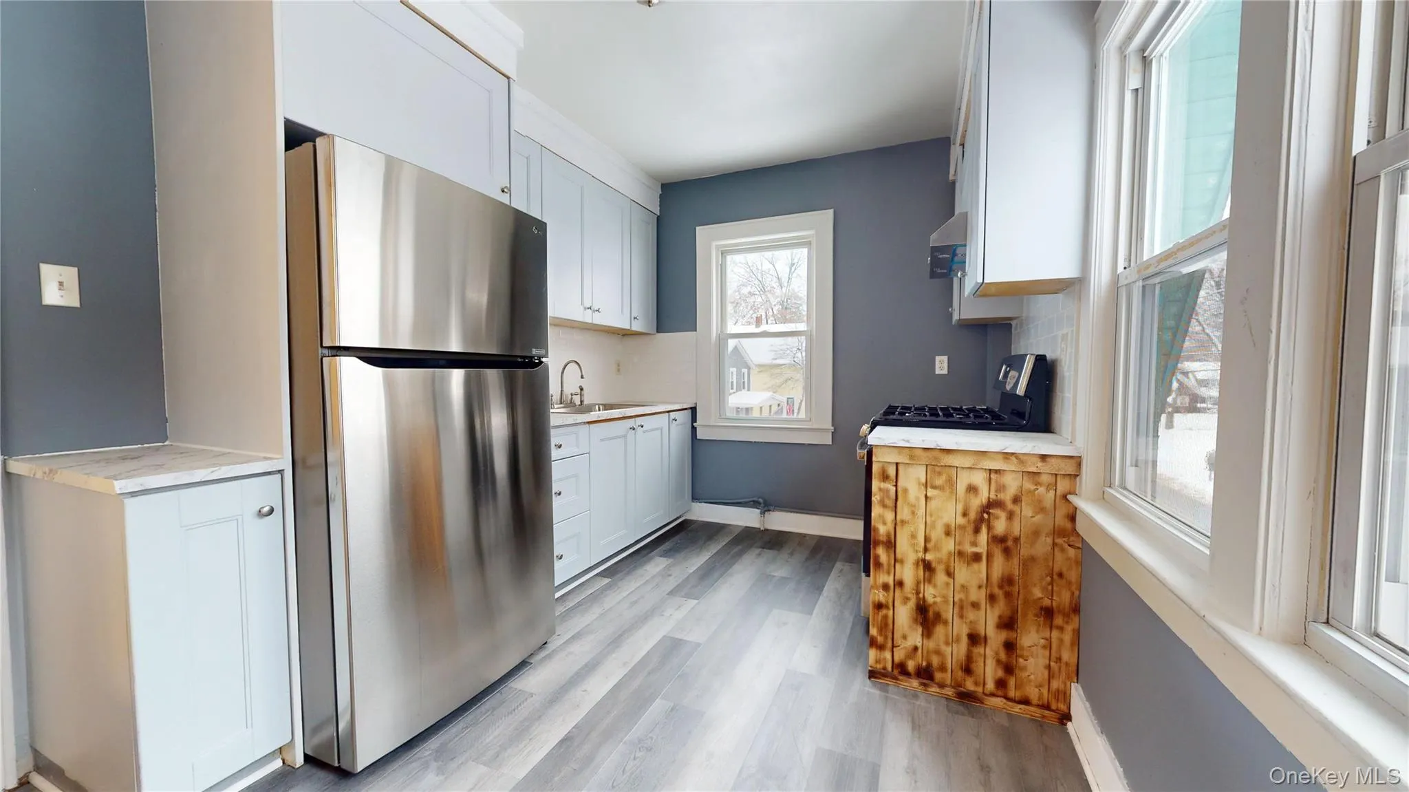 Kitchen featuring freestanding refrigerator, light countertops, white cabinetry, and backsplash Kitchen featuring freestanding refrigerator, light countertops, white cabinetry, and backsplash