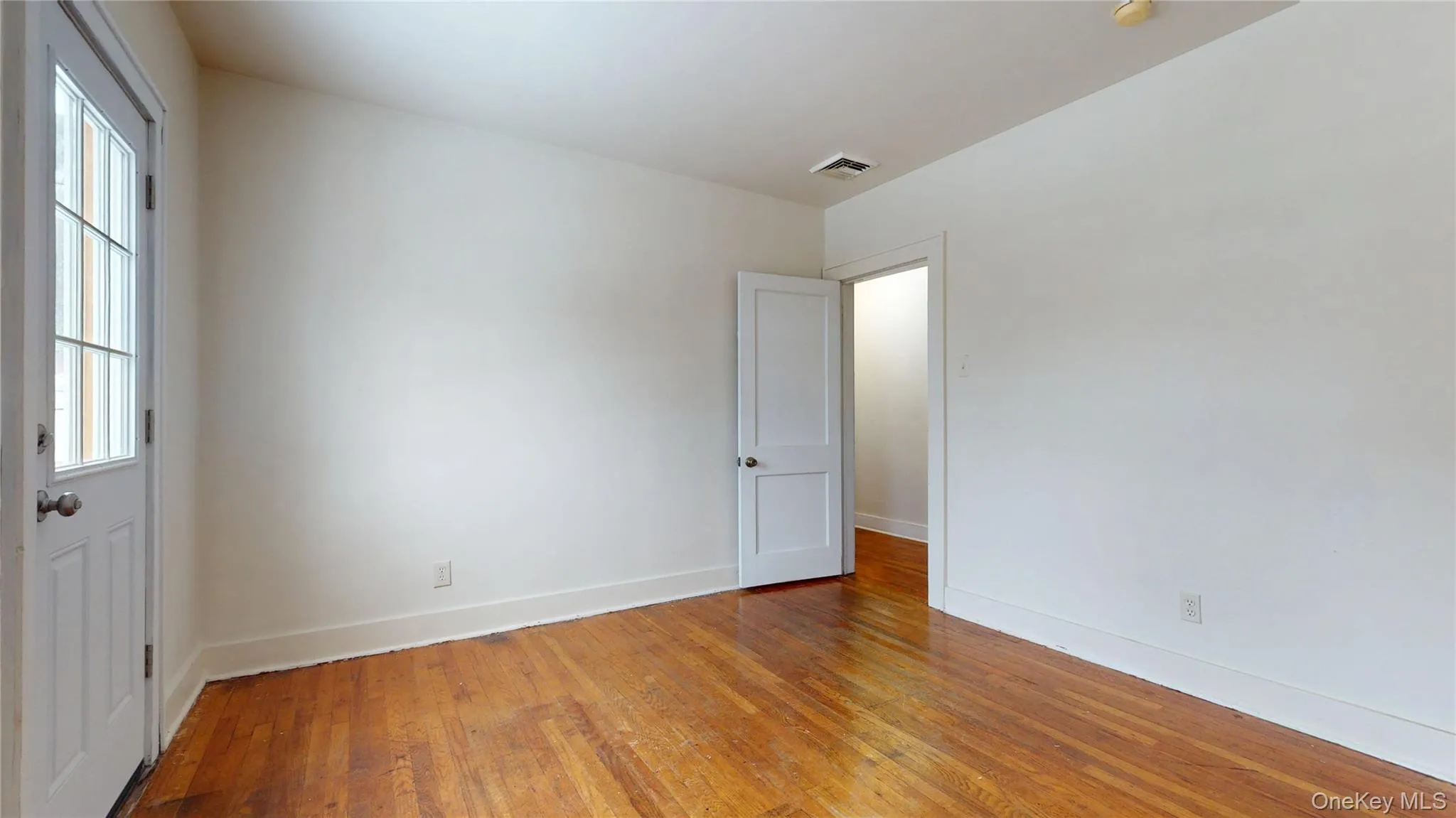 Spare room featuring wood-type flooring and baseboards Spare room featuring wood-type flooring and baseboards