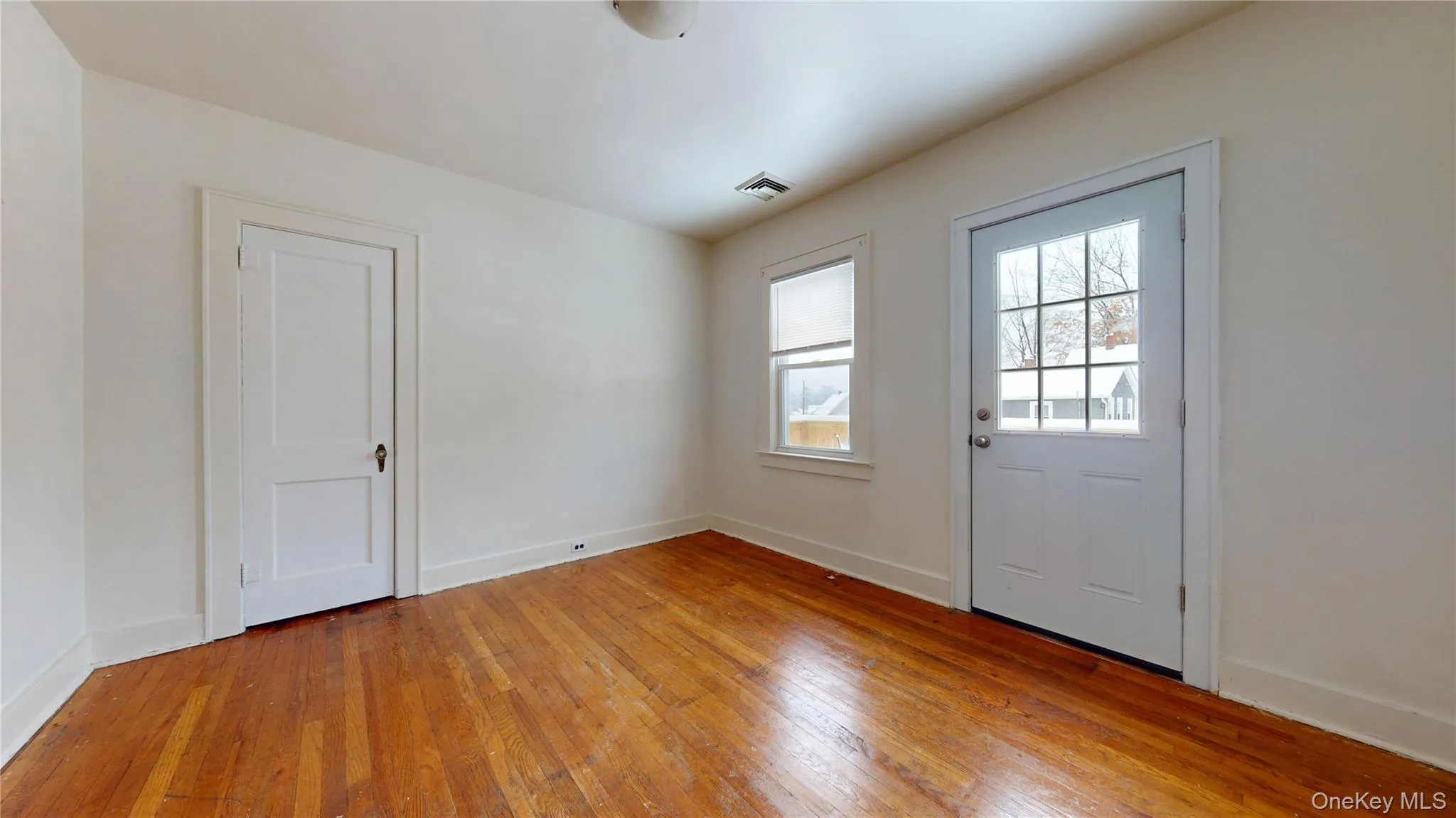 Doorway to outside featuring hardwood / wood-style flooring and baseboards Doorway to outside featuring hardwood / wood-style flooring and baseboards