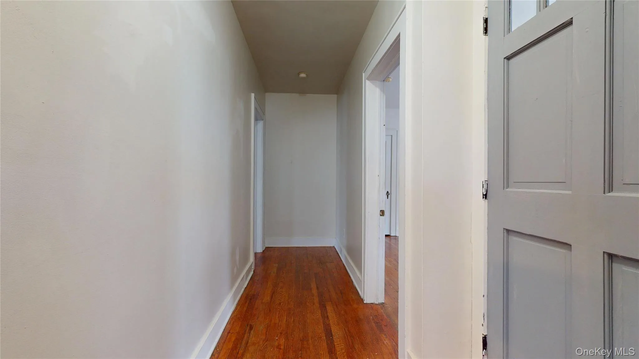 Hallway featuring dark wood-style floors and baseboards Hallway featuring dark wood-style floors and baseboards