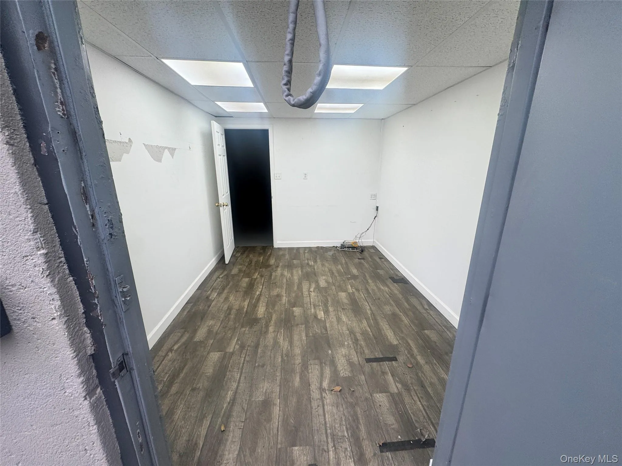 Unfurnished room with dark wood finished floors and a paneled ceiling Unfurnished room with dark wood finished floors and a paneled ceiling