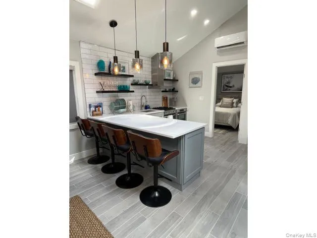 Kitchen with light countertops, lofted ceiling, open shelves, a kitchen breakfast bar, and a peninsula Kitchen with light countertops, lofted ceiling, open shelves, a kitchen breakfast bar, and a peninsula