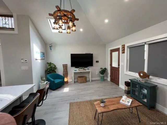 Living area featuring a chandelier, wood tiled floors, and high vaulted ceiling Living area featuring a chandelier, wood tiled floors, and high vaulted ceiling