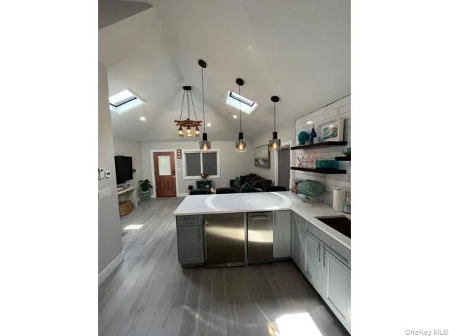 Kitchen featuring a peninsula, pendant lighting, open shelves, a skylight, and vaulted ceiling Kitchen featuring a peninsula, pendant lighting, open shelves, a skylight, and vaulted ceiling