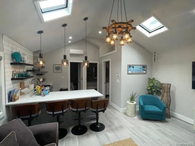 Kitchen featuring a skylight, a peninsula, a kitchen breakfast bar, decorative light fixtures, and light wood-type flooring Kitchen featuring a skylight, a peninsula, a kitchen breakfast bar, decorative light fixtures, and light wood-type flooring