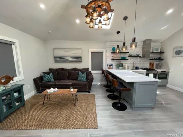 Kitchen featuring open shelves, a kitchen breakfast bar, decorative light fixtures, a peninsula, and a chandelier Kitchen featuring open shelves, a kitchen breakfast bar, decorative light fixtures, a peninsula, and a chandelier