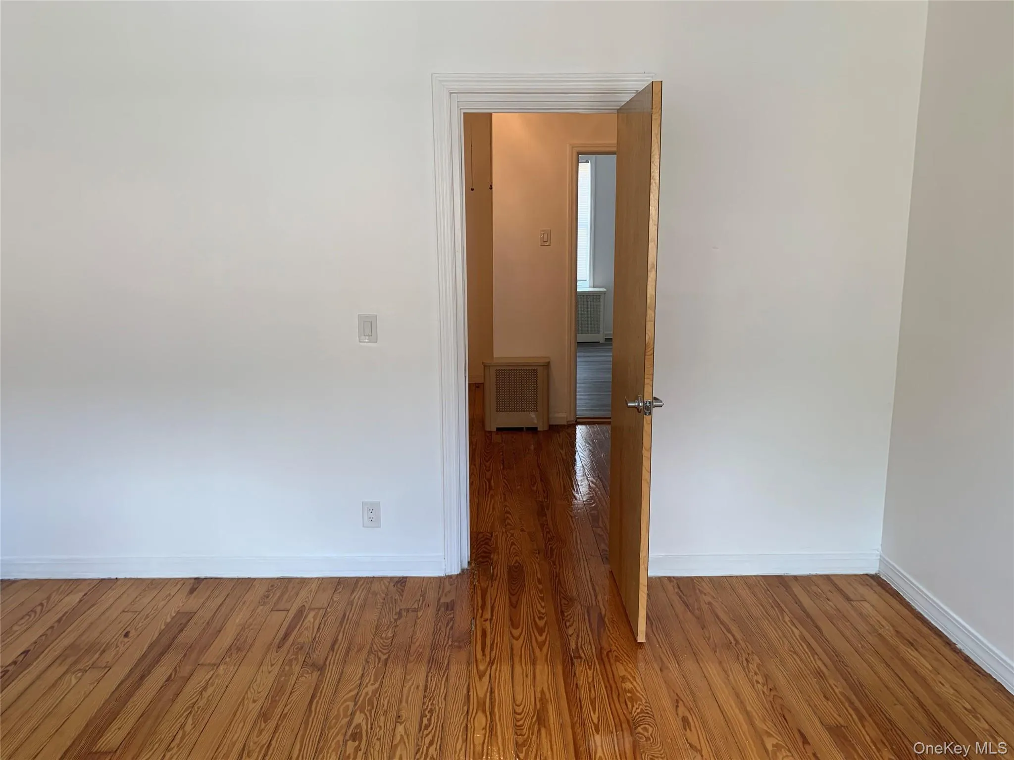 Spare room with wood finished floors and radiator Spare room with wood finished floors and radiator