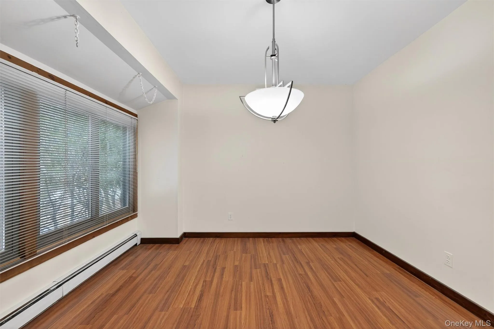 Spare room with baseboard heating and wood finished floors Spare room with baseboard heating and wood finished floors
