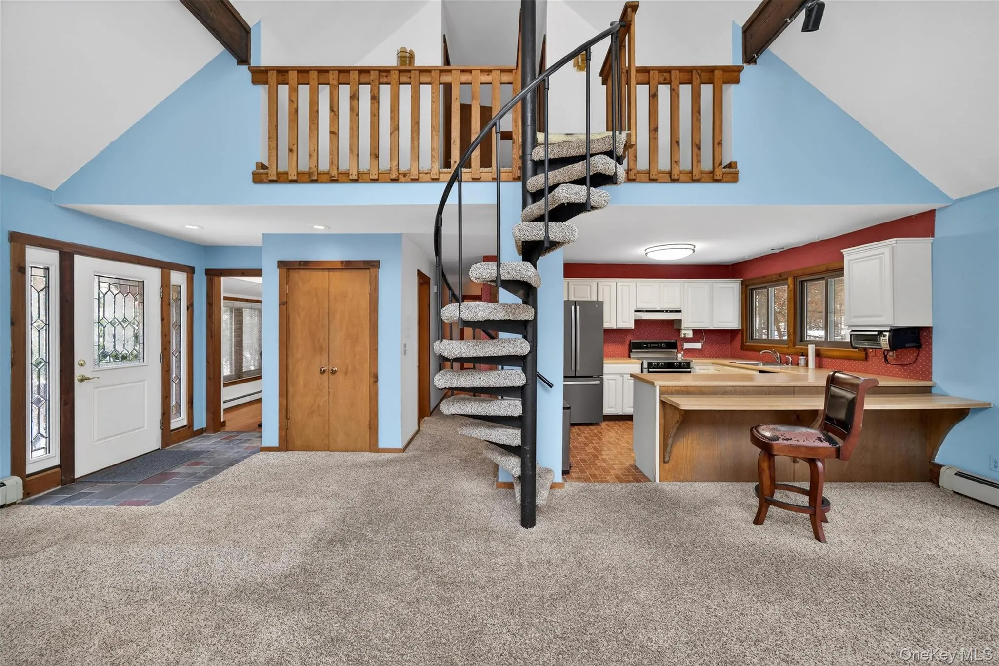 Kitchen with plenty of natural light, high vaulted ceiling, white cabinetry, light countertops, and light colored carpet Kitchen with plenty of natural light, high vaulted ceiling, white cabinetry, light countertops, and light colored carpet
