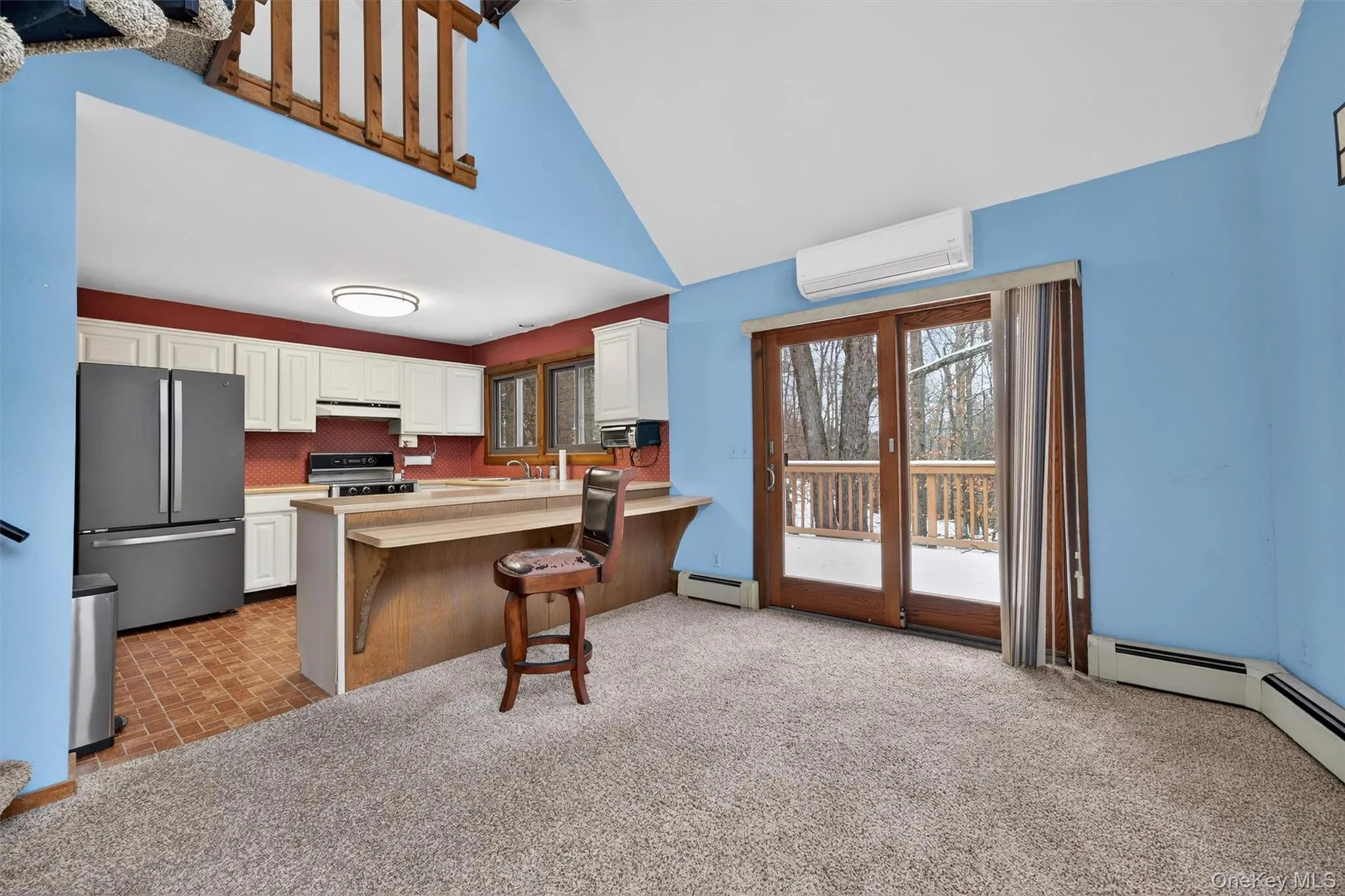 Kitchen with light colored carpet, a breakfast bar, stainless steel appliances, white cabinets, and light countertops Kitchen with light colored carpet, a breakfast bar, stainless steel appliances, white cabinets, and light countertops