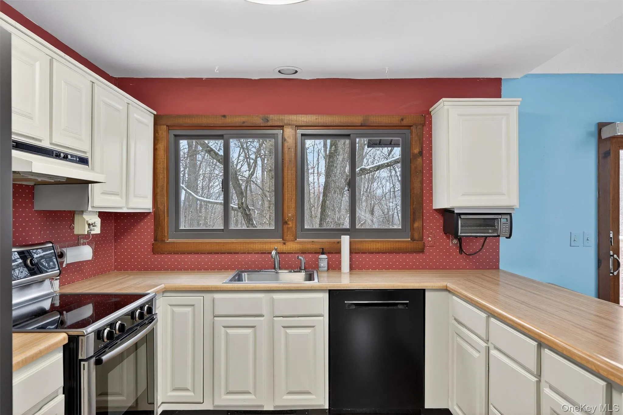 Kitchen featuring stainless steel range with electric cooktop, white cabinetry, black dishwasher, and light countertops Kitchen featuring stainless steel range with electric cooktop, white cabinetry, black dishwasher, and light countertops