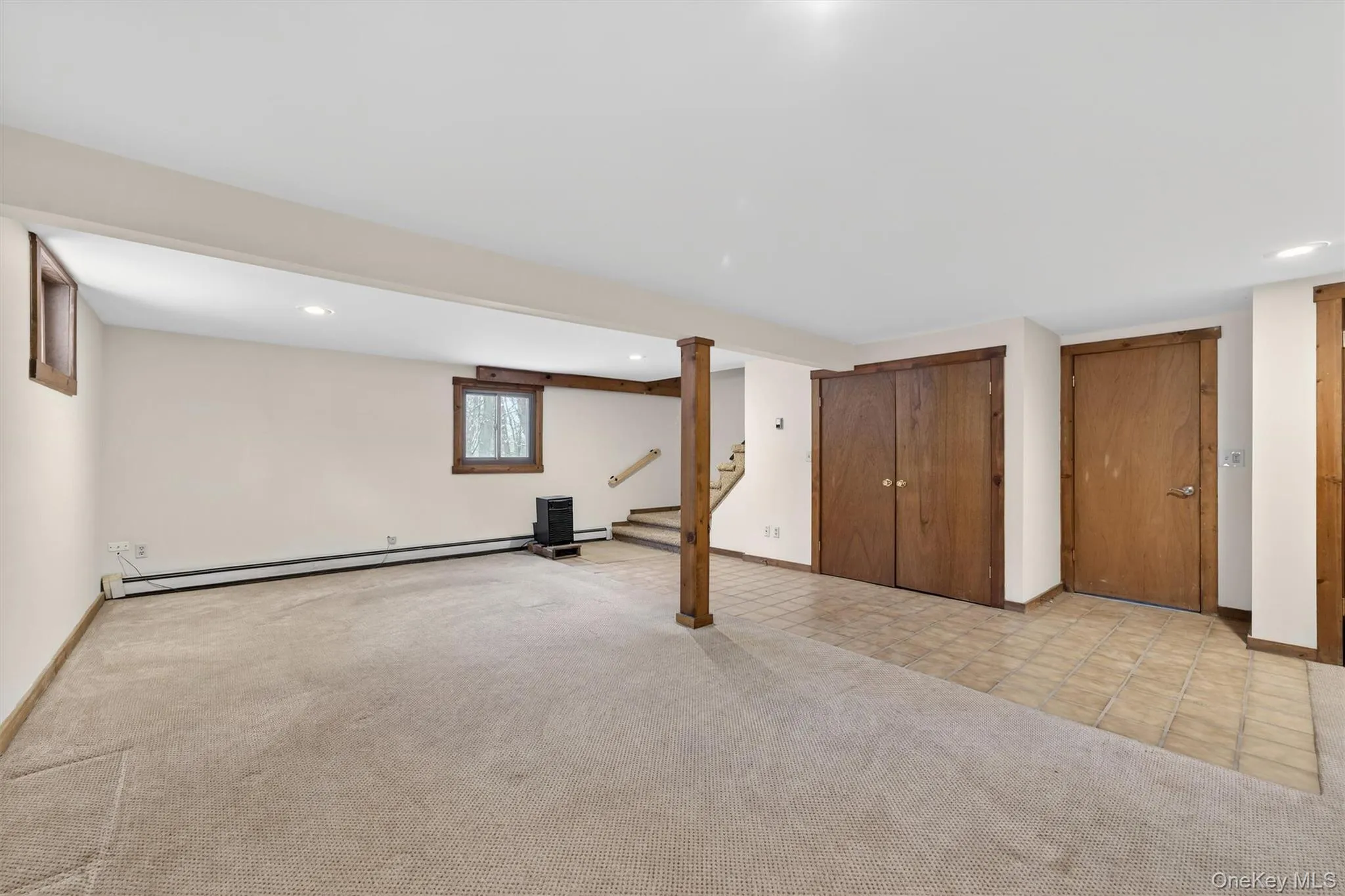 Basement featuring stairs, light colored carpet, baseboard heating, light tile patterned flooring, and recessed lighting Basement featuring stairs, light colored carpet, baseboard heating, light tile patterned flooring, and recessed lighting