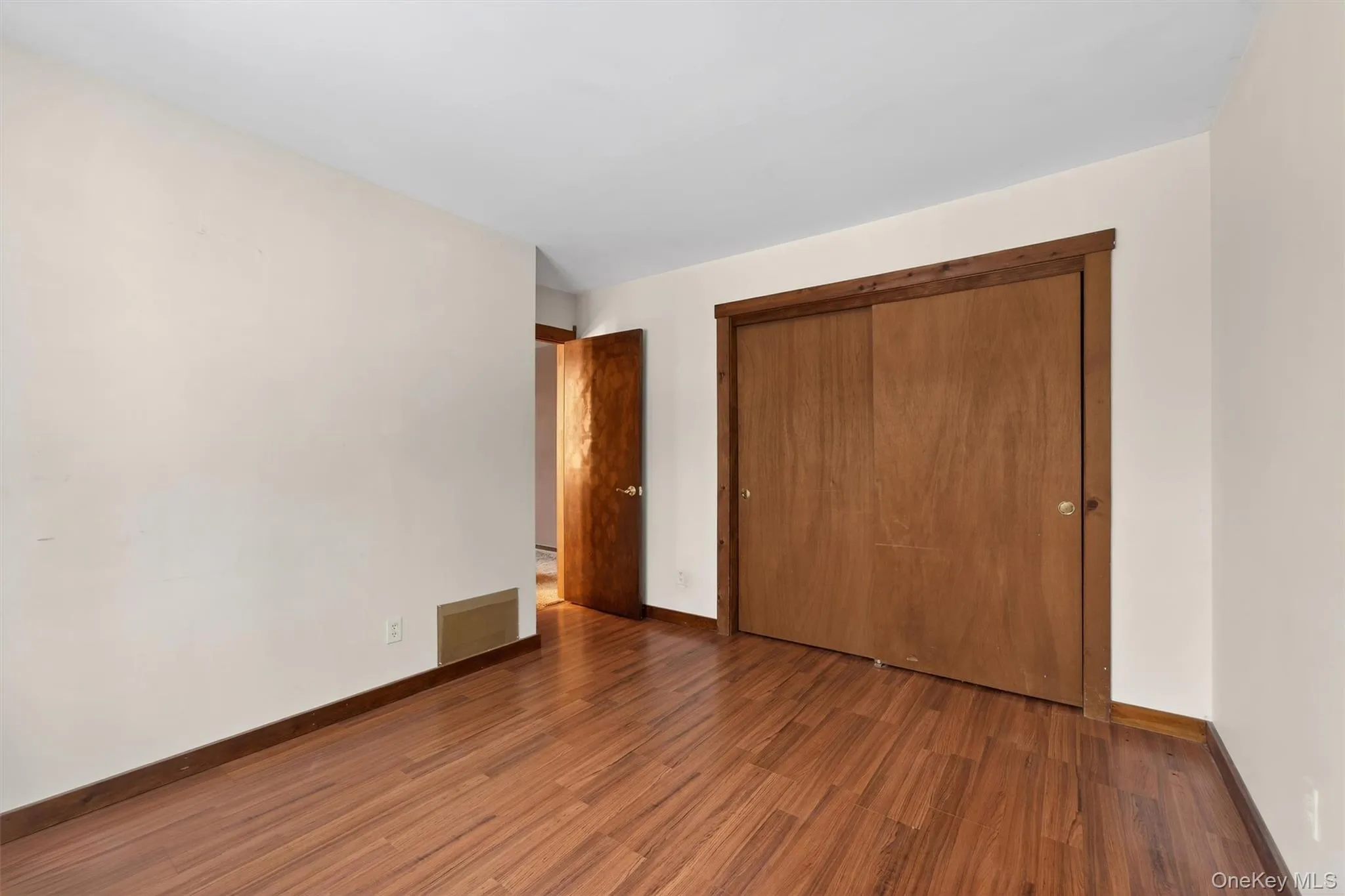 Unfurnished bedroom featuring dark wood-type flooring and a closet Unfurnished bedroom featuring dark wood-type flooring and a closet
