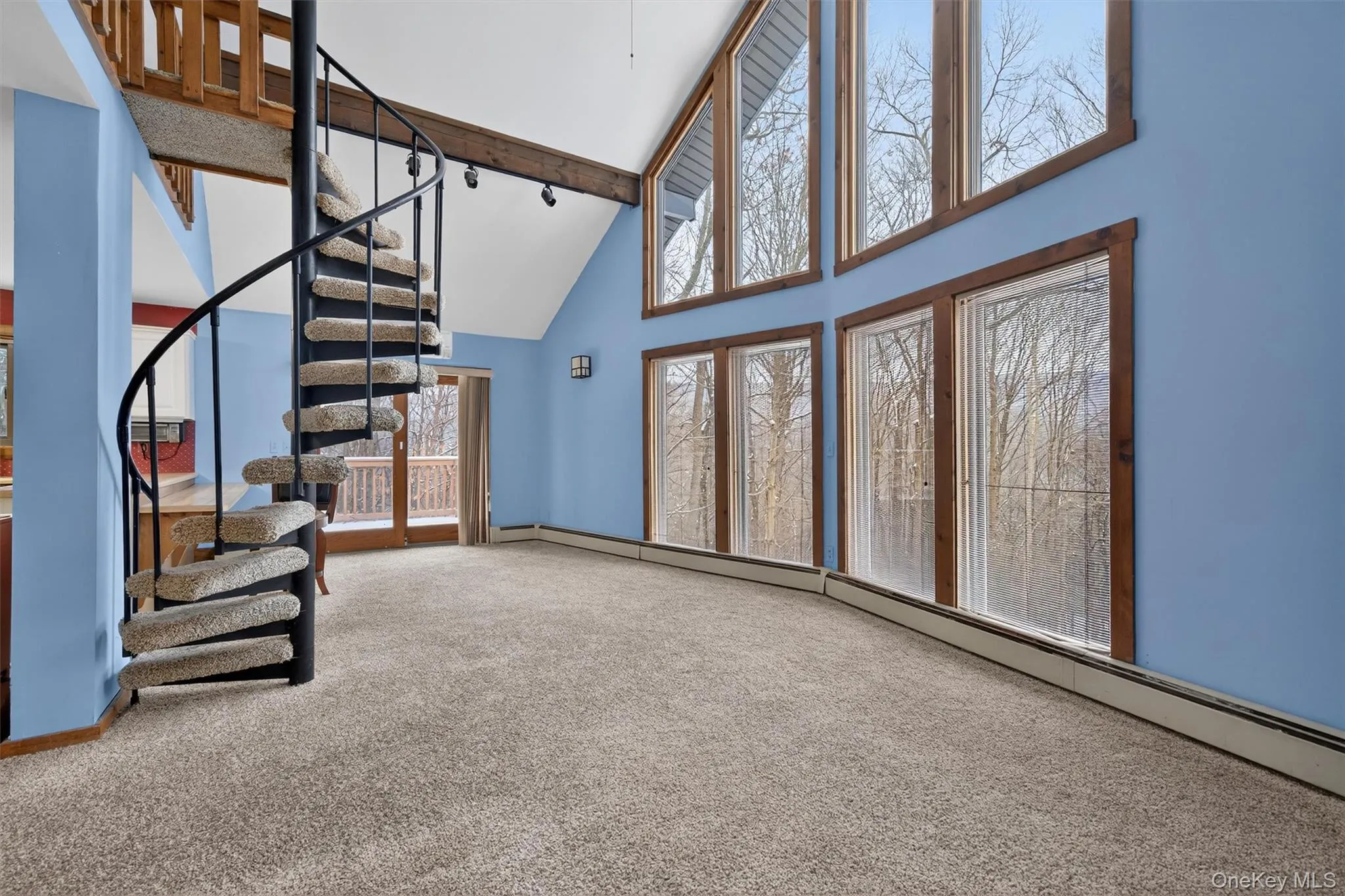 Unfurnished living room with baseboard heating, carpet floors, high vaulted ceiling, stairs, and beamed ceiling Unfurnished living room with baseboard heating, carpet floors, high vaulted ceiling, stairs, and beamed ceiling