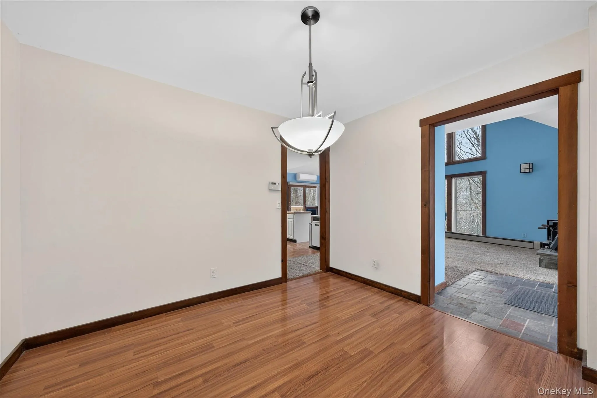 Unfurnished dining area with wood finished floors and baseboard heating Unfurnished dining area with wood finished floors and baseboard heating